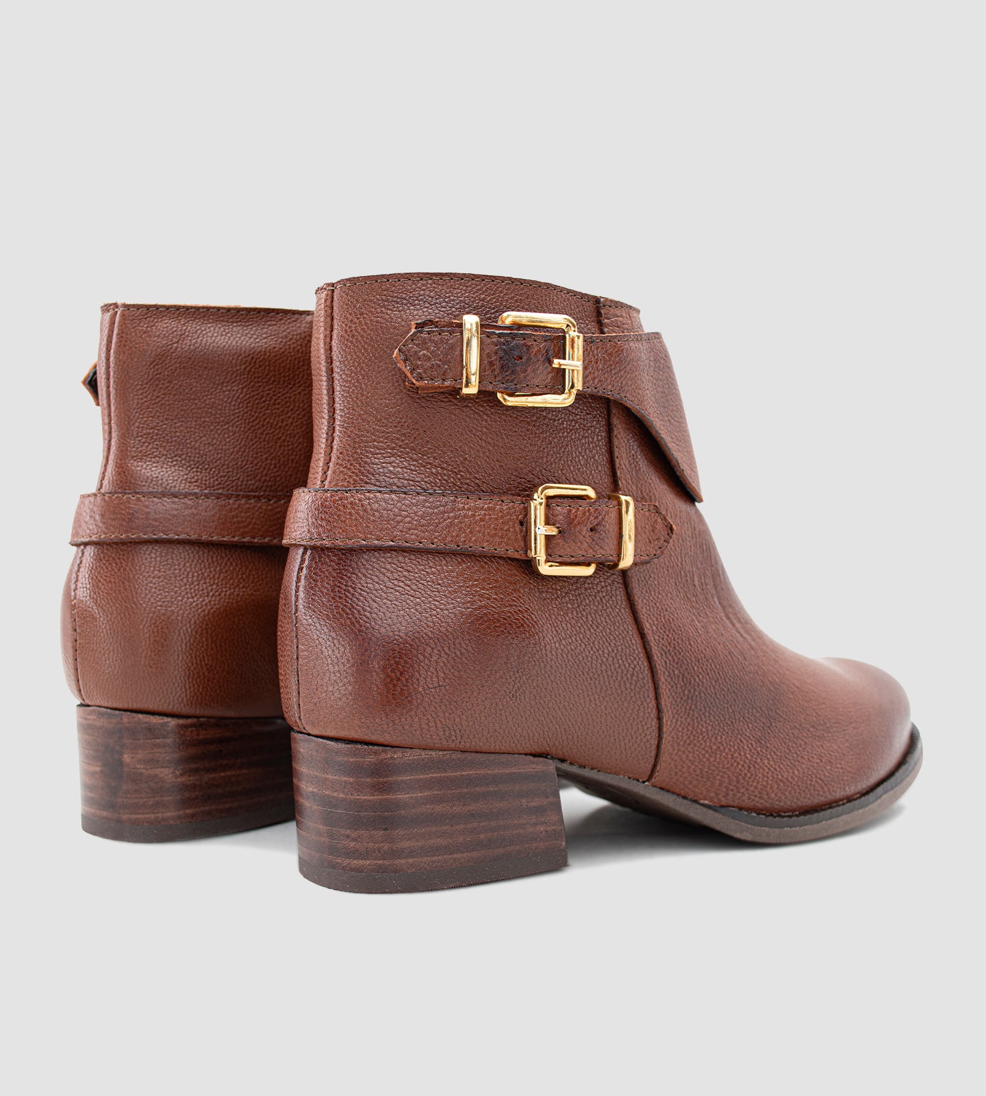 Bota feminina de cano curto em couro legítimo marrom, com acabamento texturizado e design elegante, destacando duas fivelas metálicas douradas que agregam sofisticação ao modelo. O salto grosso baixo, aliado ao solado emborrachado, proporciona conforto e segurança no uso diário. Versátil e atemporal, essa bota é ideal para compor looks clássicos com um toque moderno, perfeita para dias mais frios ou produções urbanas com personalidade.