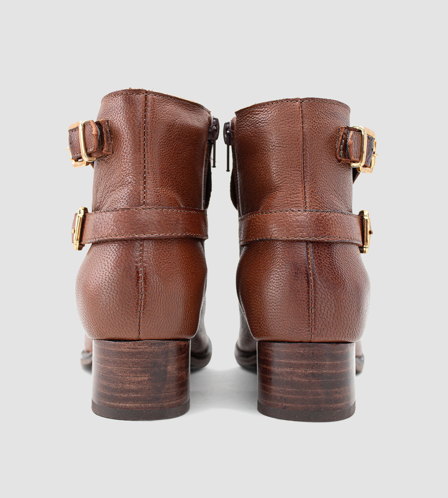 Bota feminina de cano curto em couro legítimo marrom, com acabamento texturizado e design elegante, destacando duas fivelas metálicas douradas que agregam sofisticação ao modelo. O salto grosso baixo, aliado ao solado emborrachado, proporciona conforto e segurança no uso diário. Versátil e atemporal, essa bota é ideal para compor looks clássicos com um toque moderno, perfeita para dias mais frios ou produções urbanas com personalidade.