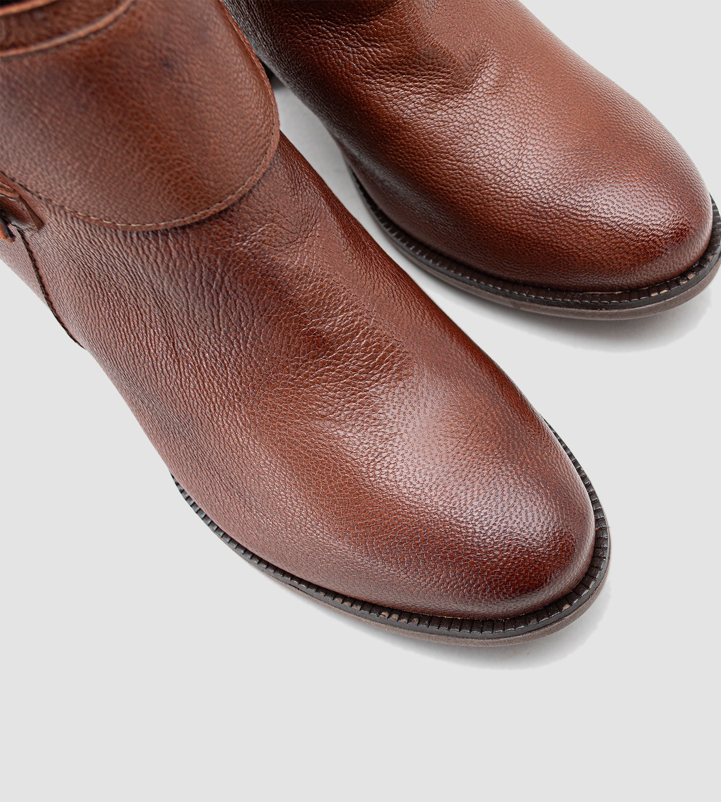 Bota feminina de cano curto em couro legítimo marrom, com acabamento texturizado e design elegante, destacando duas fivelas metálicas douradas que agregam sofisticação ao modelo. O salto grosso baixo, aliado ao solado emborrachado, proporciona conforto e segurança no uso diário. Versátil e atemporal, essa bota é ideal para compor looks clássicos com um toque moderno, perfeita para dias mais frios ou produções urbanas com personalidade.