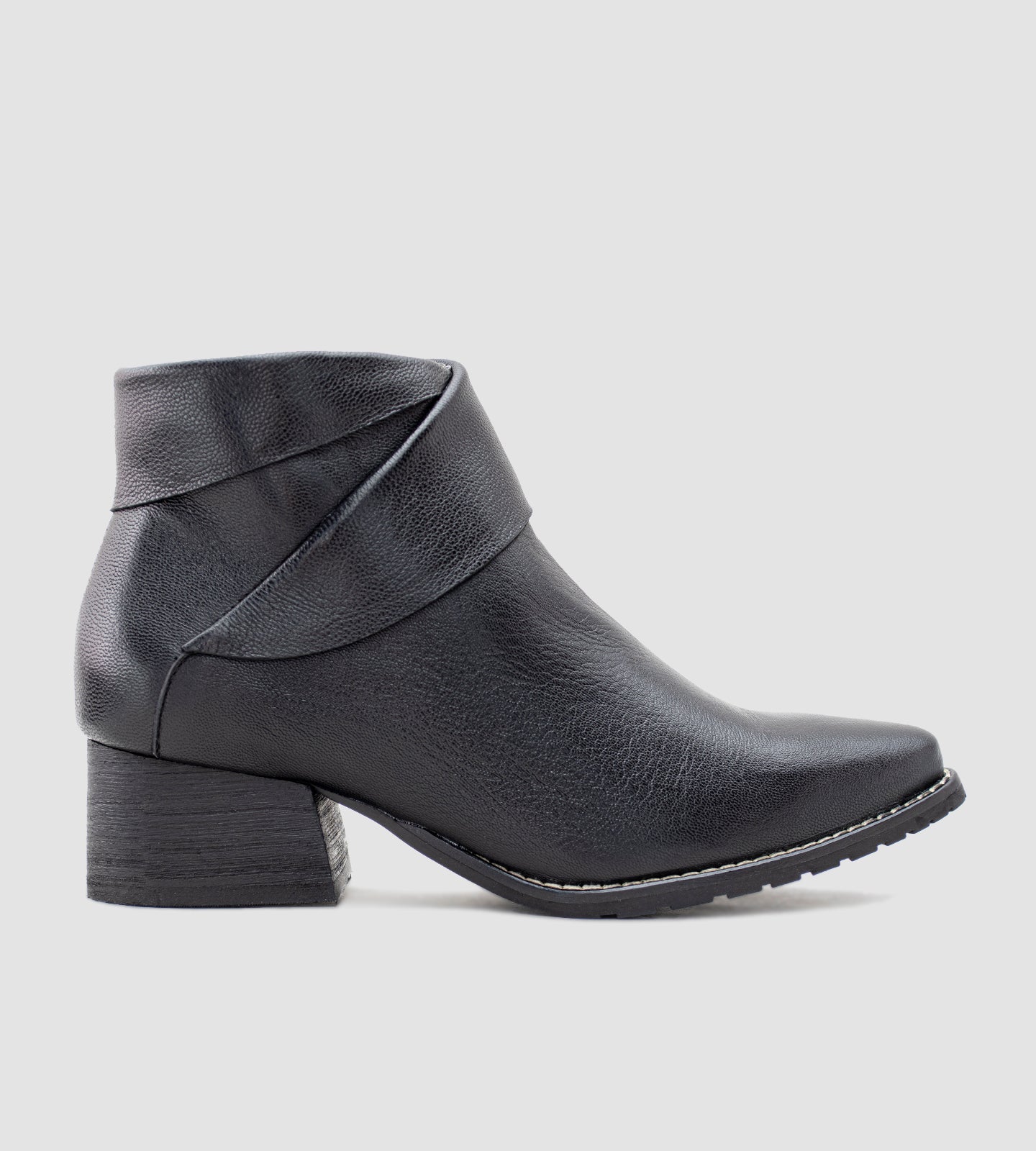 Bota feminina de cano curto confeccionada em couro legítimo preto, com acabamento texturizado e detalhe transpassado no tornozelo que traz um toque moderno e sofisticado ao design. Com salto grosso baixo e solado emborrachado, é uma peça versátil e confortável, ideal para compor looks elegantes no dia a dia ou em produções urbanas.