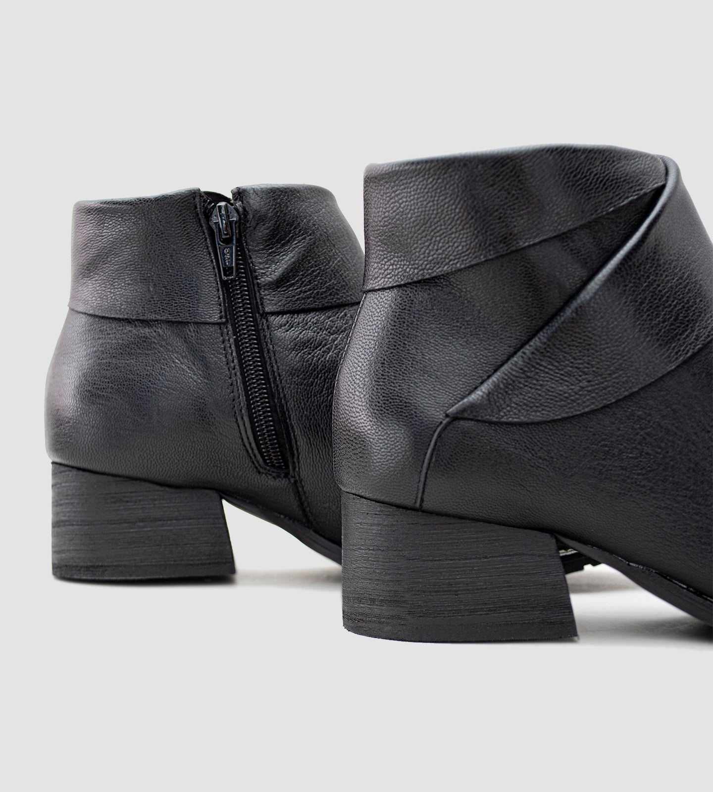 Bota feminina de cano curto confeccionada em couro legítimo preto, com acabamento texturizado e detalhe transpassado no tornozelo que traz um toque moderno e sofisticado ao design. Com salto grosso baixo e solado emborrachado, é uma peça versátil e confortável, ideal para compor looks elegantes no dia a dia ou em produções urbanas.