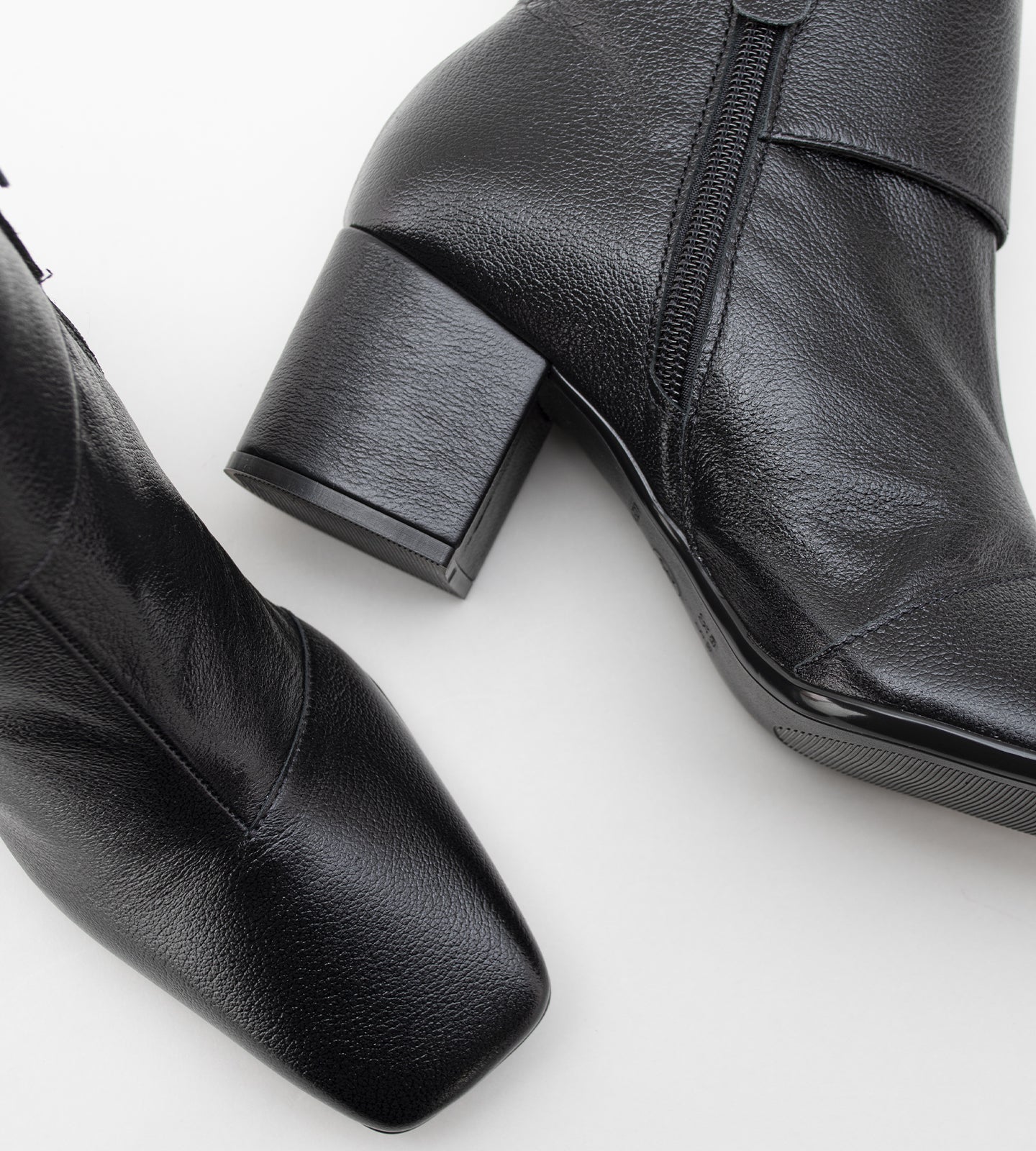 Bota feminina cano médio em couro preto com bico quadrado, salto bloco médio e fechamento em zíper lateral, design moderno e elegante.