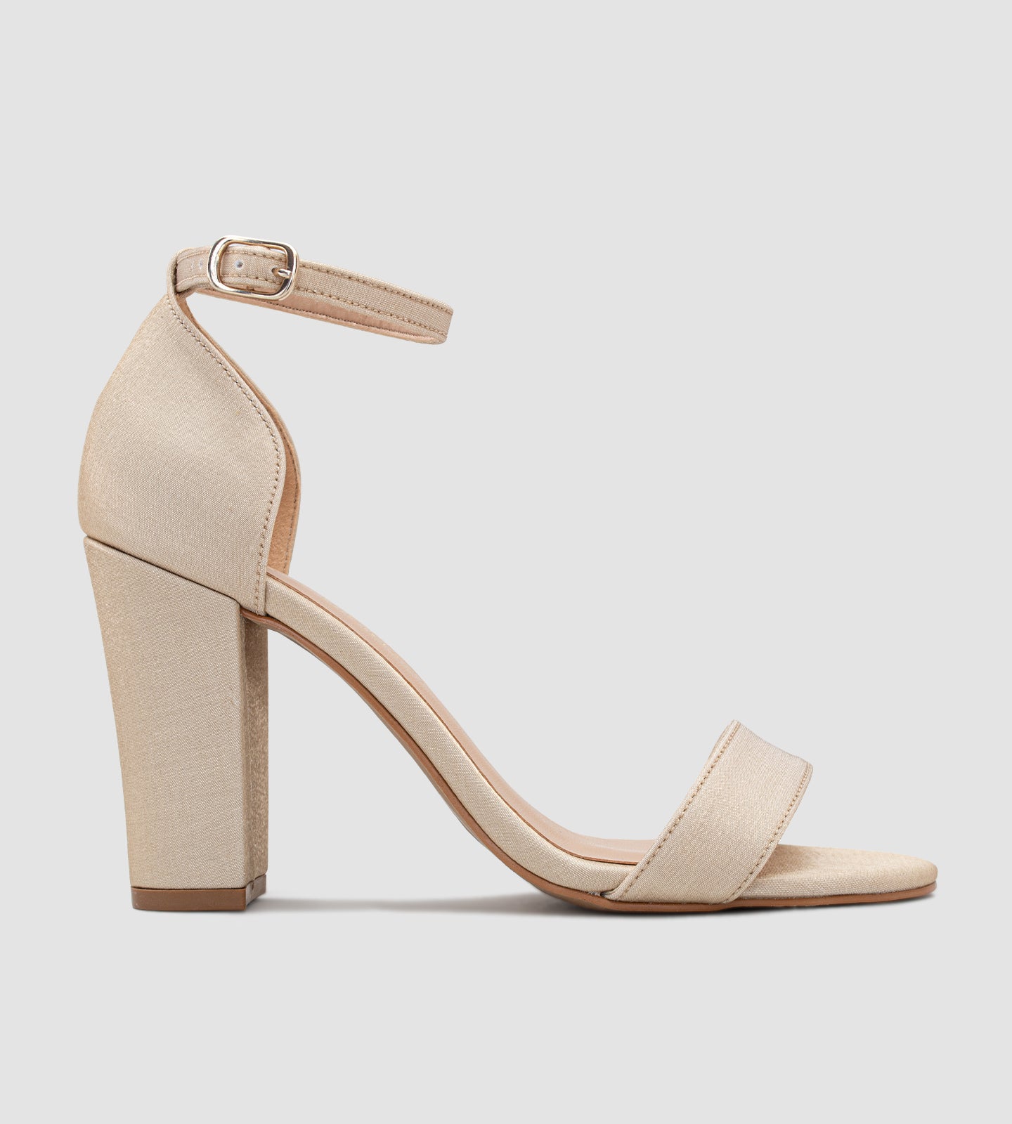 Imagem de uma sandália modelo Gisele na cor areia, feita em tecido velvet. O design apresenta uma tira única sobre os dedos, salto grosso de 10 cm de altura e fecho com fivela no tornozelo. Uma opção elegante e confortável para eventos especiais.