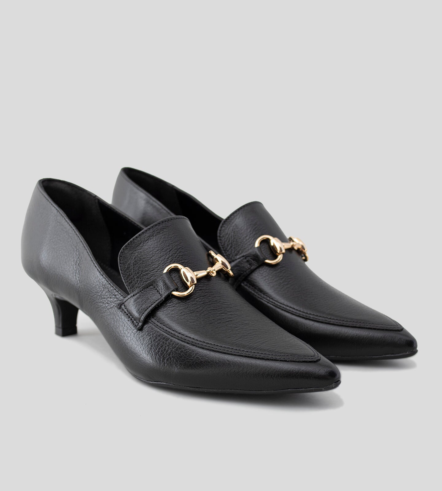Scarpin mocassim feminino em couro preto, com salto baixo de aproximadamente 5 cm e detalhe de metal dourado no cabedal, exibindo um design clássico e sofisticado.