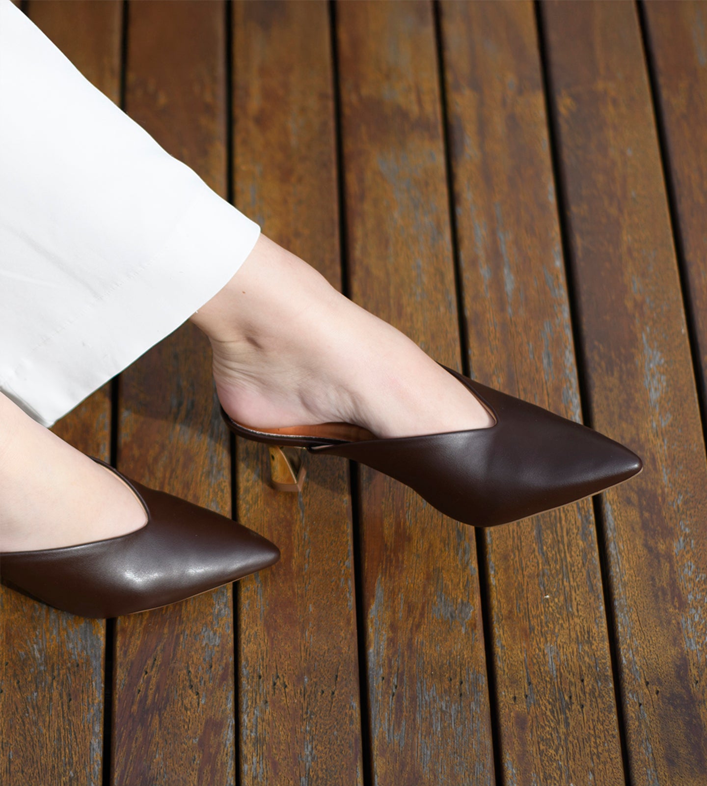 Mule marrom em napa com bico fino e salto dourado escultural de 7cm, combinando design moderno, elegância e conforto.