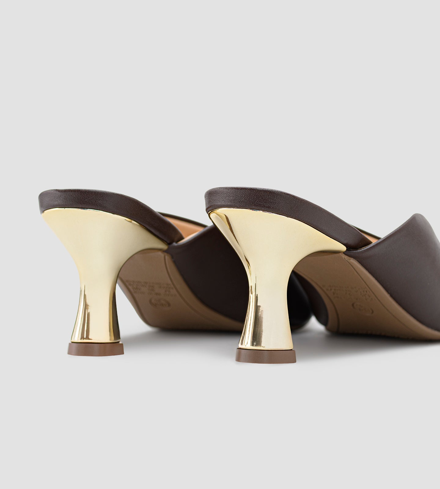 Mule marrom em napa com bico fino e salto dourado escultural de 7cm, combinando design moderno, elegância e conforto.