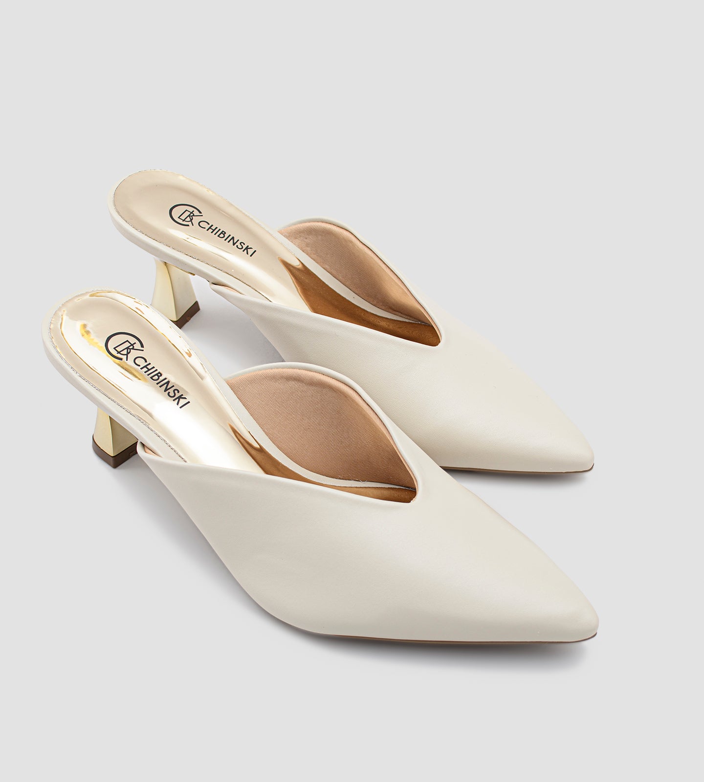 Mule nude em napa com bico fino e salto dourado escultural de 7cm, combinando design moderno, elegância e conforto.