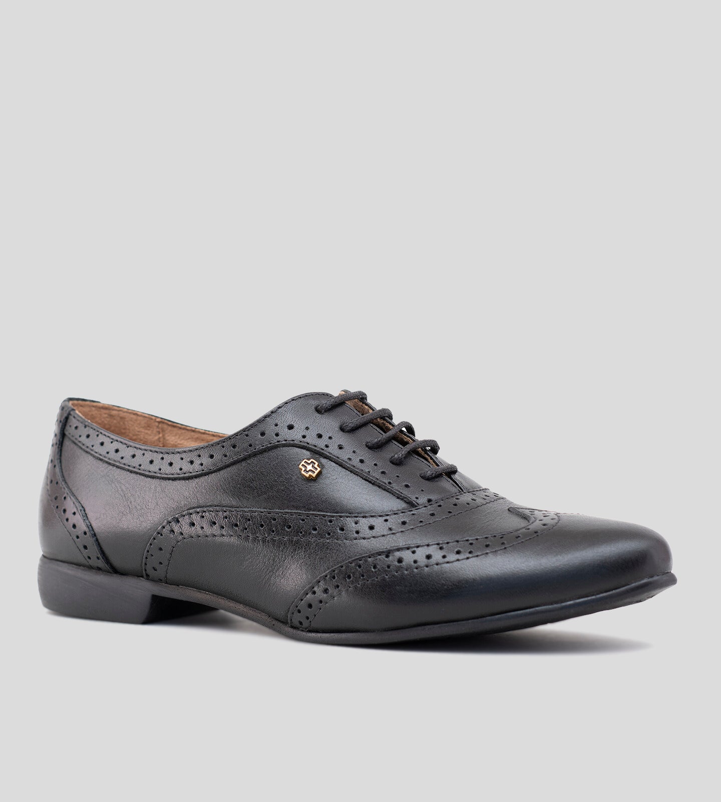 Sapato Oxford feminino em couro preto, com design clássico e detalhes brogue perfurados. Modelo elegante e versátil, possui fechamento por cadarço e solado baixo, ideal para compor looks sofisticados e casuais com conforto.