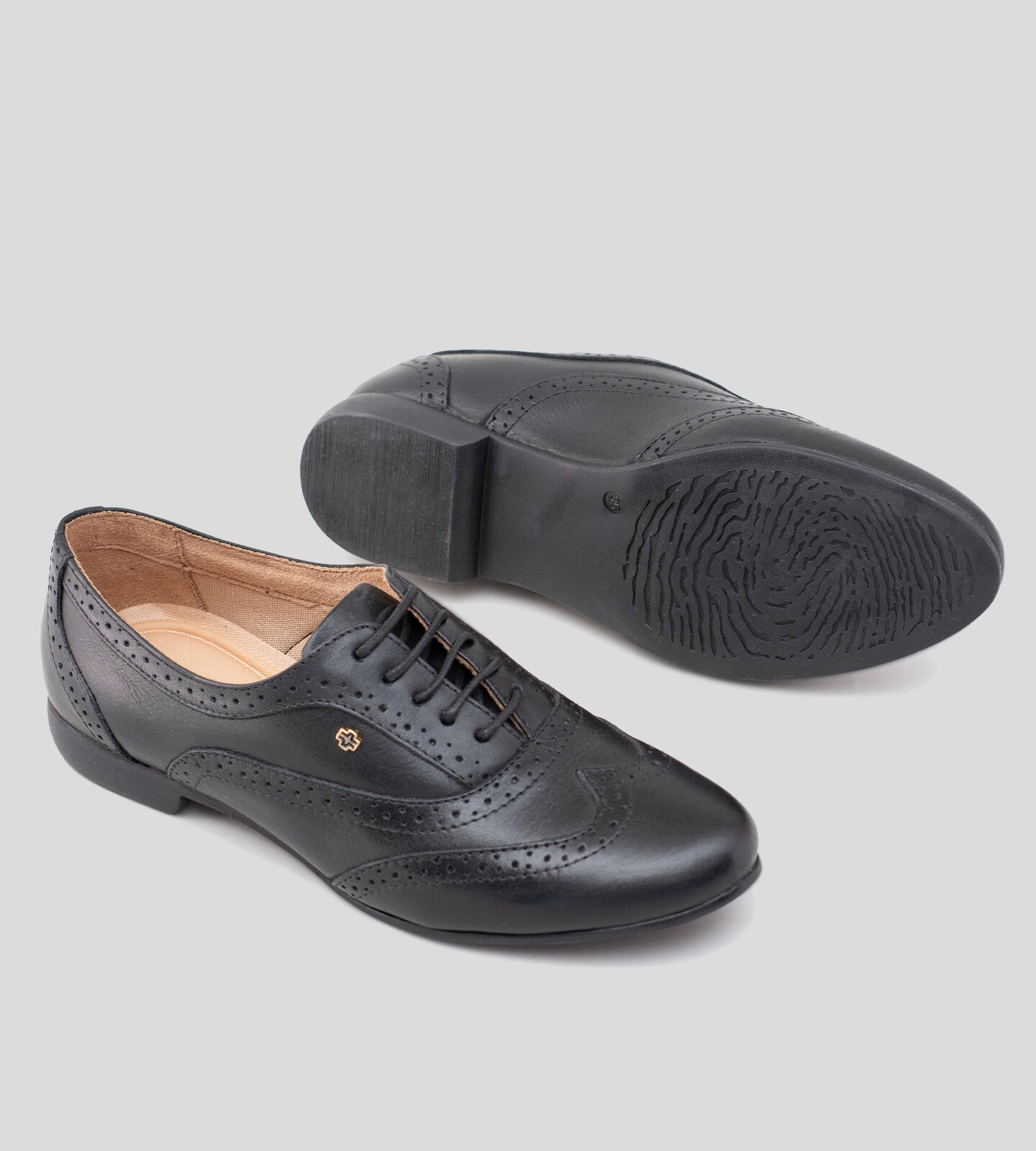 Sapato Oxford feminino em couro preto, com design clássico e detalhes brogue perfurados. Modelo elegante e versátil, possui fechamento por cadarço e solado baixo, ideal para compor looks sofisticados e casuais com conforto.