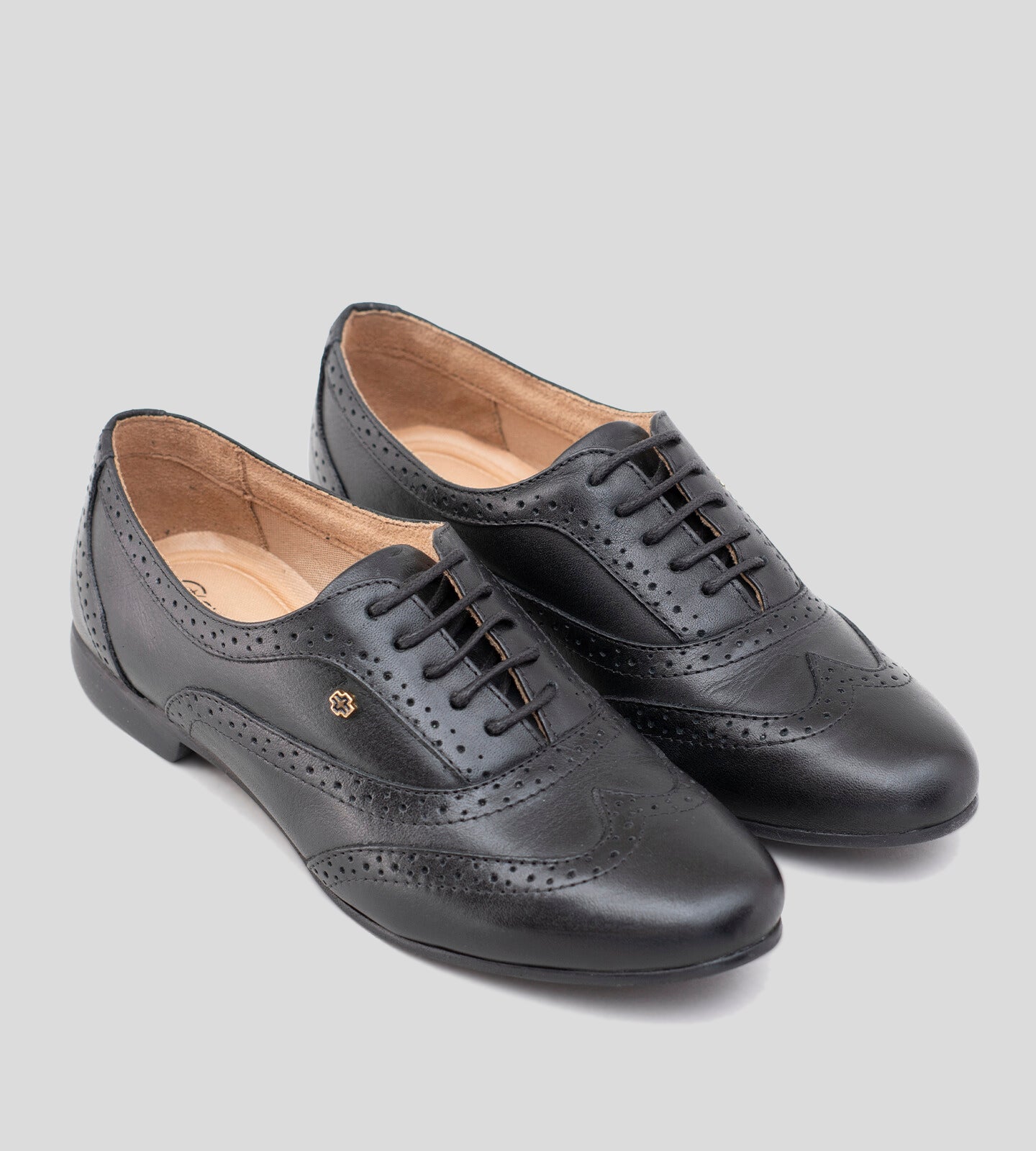 Sapato Oxford feminino em couro preto, com design clássico e detalhes brogue perfurados. Modelo elegante e versátil, possui fechamento por cadarço e solado baixo, ideal para compor looks sofisticados e casuais com conforto.