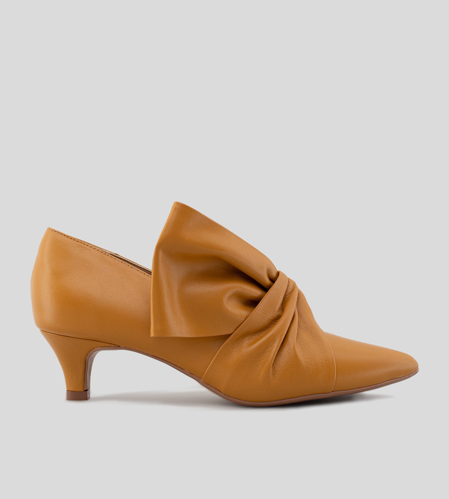 Scarpin feminino de couro caramelo com salto baixo de 5 cm e detalhe em laço torcido no cabedal, exibindo um design elegante e sofisticado.