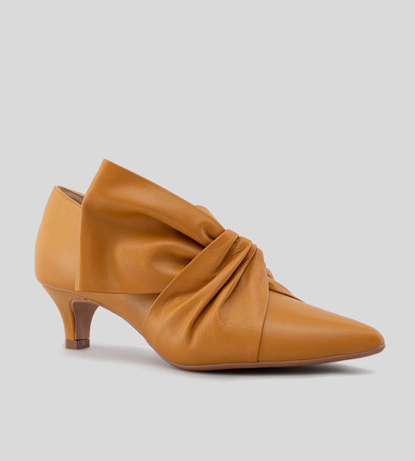 Scarpin feminino de couro caramelo com salto baixo de 5 cm e detalhe em laço torcido no cabedal, exibindo um design elegante e sofisticado.