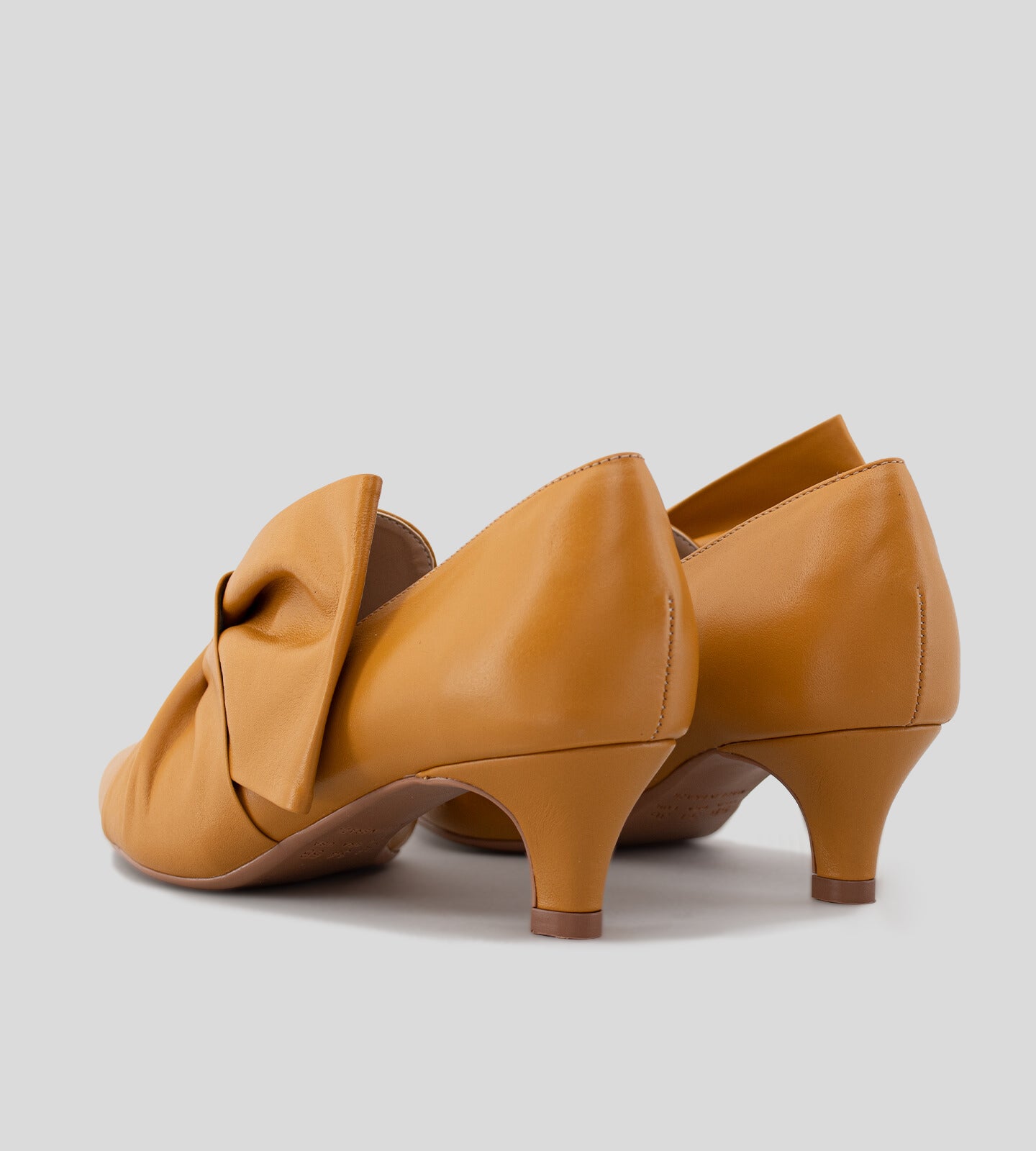 Scarpin feminino de couro caramelo com salto baixo de 5 cm e detalhe em laço torcido no cabedal, exibindo um design elegante e sofisticado.