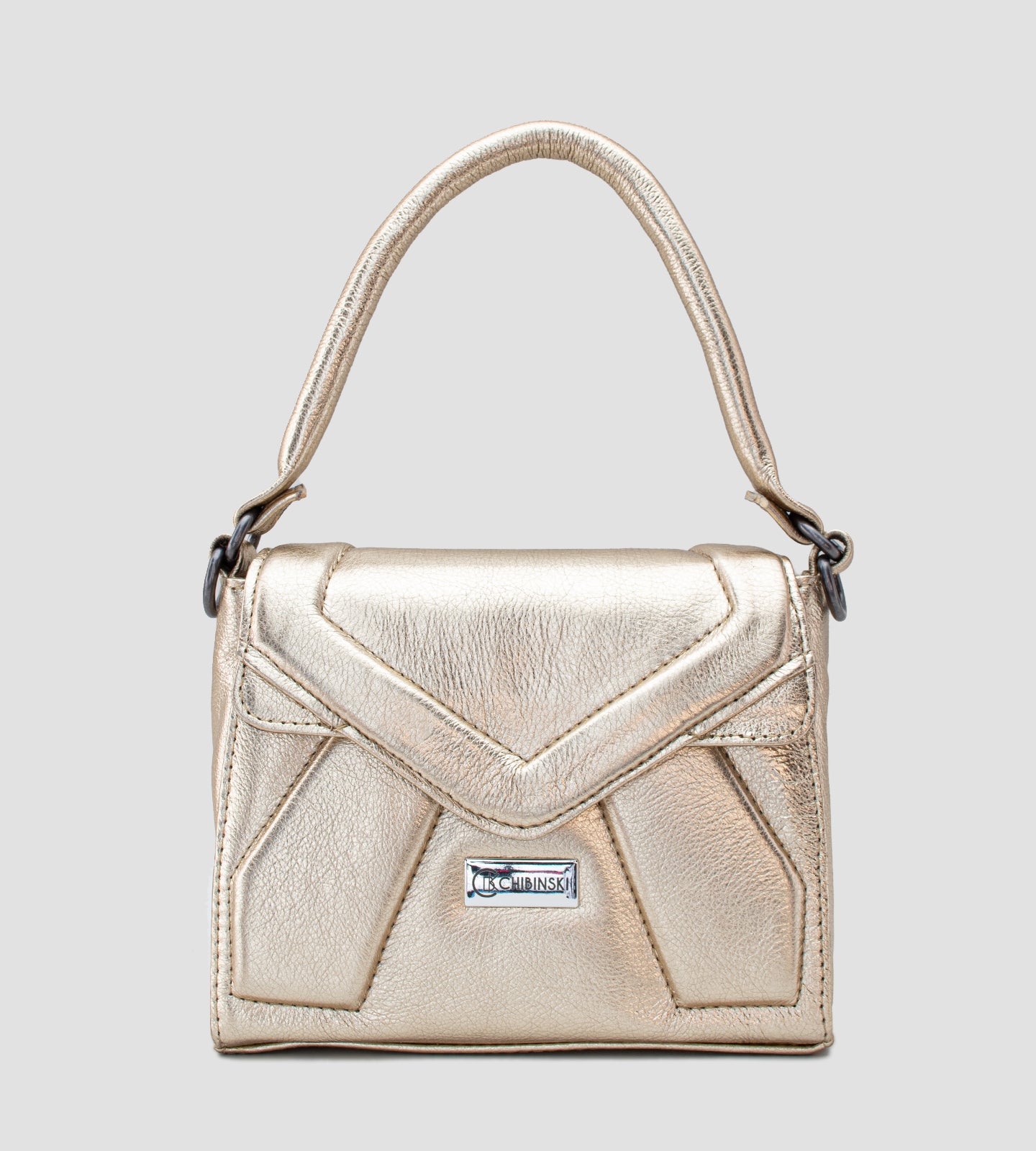 Imagem de uma bolsa feminina pequena da marca Chibinski, confeccionada em couro legítimo dourado. O design moderno apresenta linhas geométricas marcantes, acabamento metálico sofisticado e fecho frontal com a logo da marca em destaque. A bolsa possui alça de mão fixa, ideal para complementar looks elegantes em ocasiões especiais, como festas e casamentos.