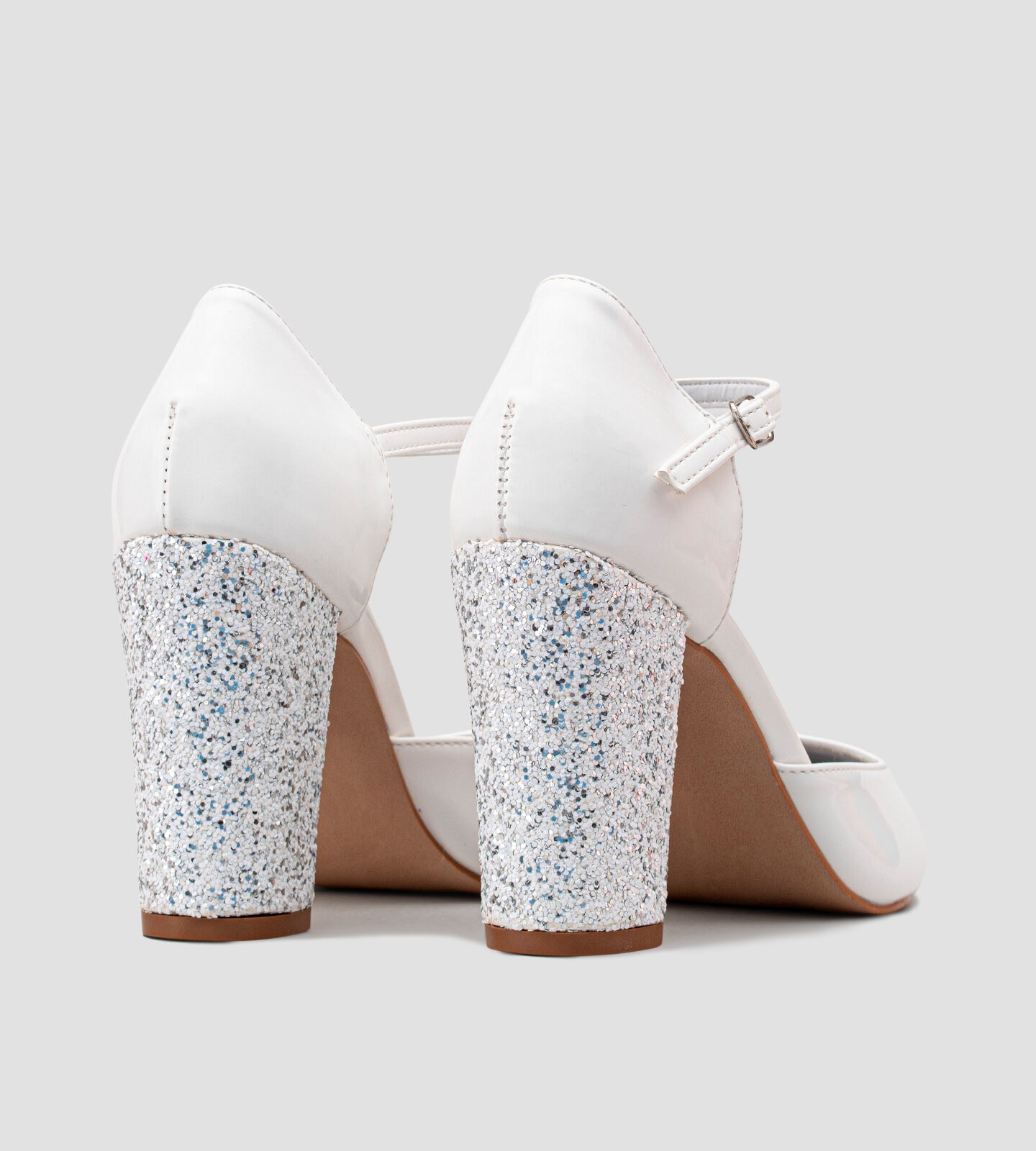 Scarpin branco em verniz com salto grosso de 10 cm, decorado com glitter. O modelo combina conforto e estilo, perfeito para eventos que pedem um toque de glamour.