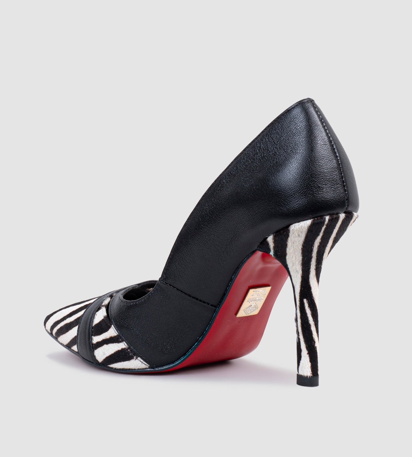 Imagem de um scarpin de salto alto 10cm com design sofisticado. O modelo apresenta a combinação de couro preto e estampa animal print zebra, destacando-se pelo bico fino elegante e detalhes em tiras sobre a estampa. O salto também acompanha a padronagem em preto e branco, criando um efeito visual marcante. A sola vermelha adiciona um toque luxuoso e diferenciado ao calçado. Ideal para compor looks ousados e sofisticados.