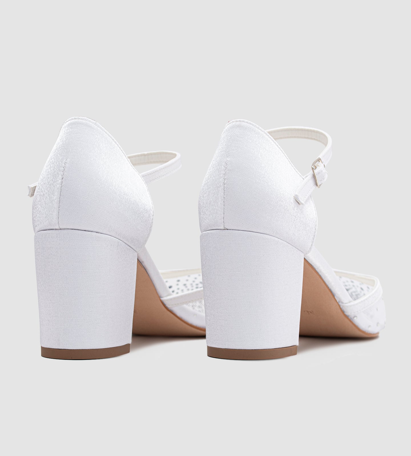 Imagem de um scarpin de noiva branco com salto bloco médio, bico fino e tira com fivela no tornozelo. A parte frontal do sapato é feita em tela delicada com aplicações de pedrarias, criando um efeito brilhante e sofisticado. O calçado combina elegância e conforto, ideal para ocasiões especiais como casamentos e festas.