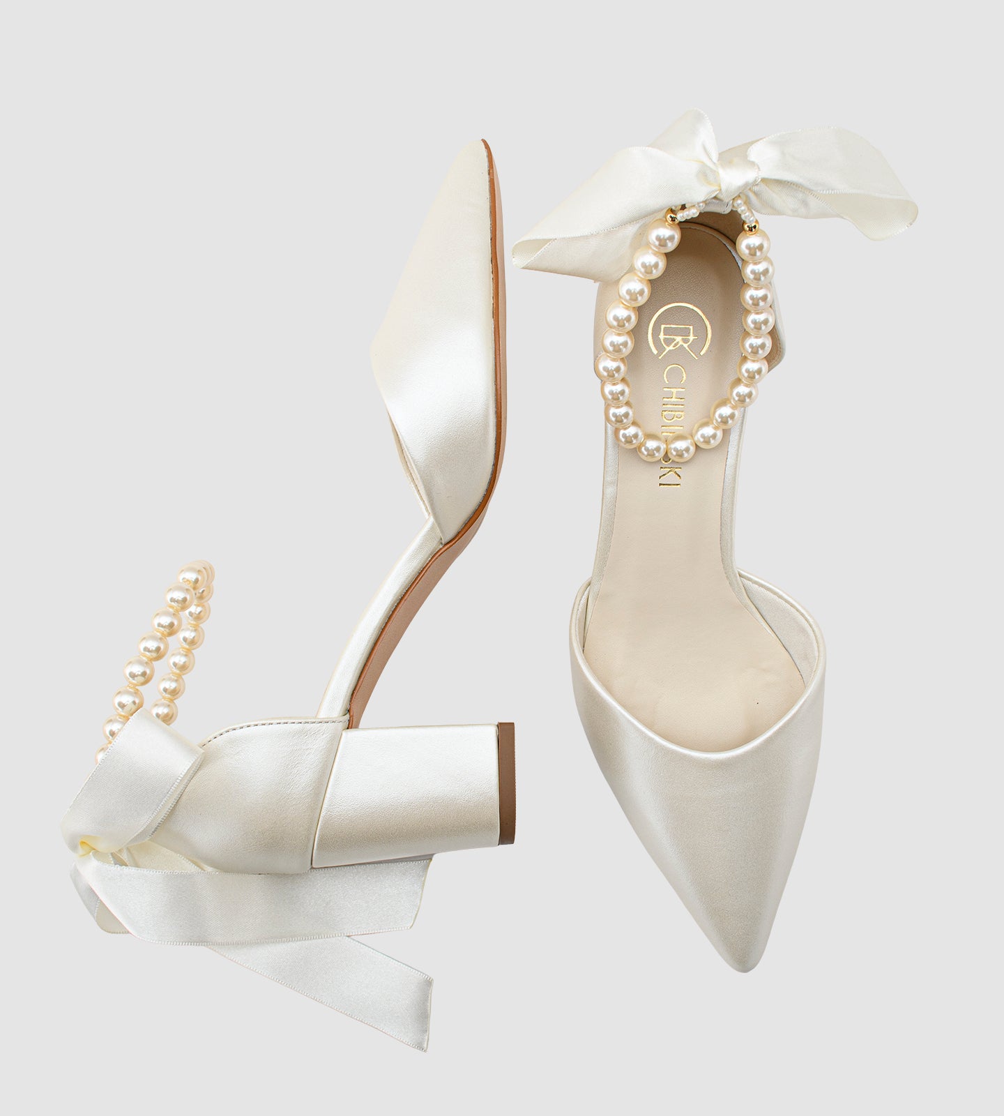 Sandália de noiva em couro perolado off white com salto bloco de 7cm, bico fino e tornozeleira de pérolas com laço de cetim, ideal para casamento.