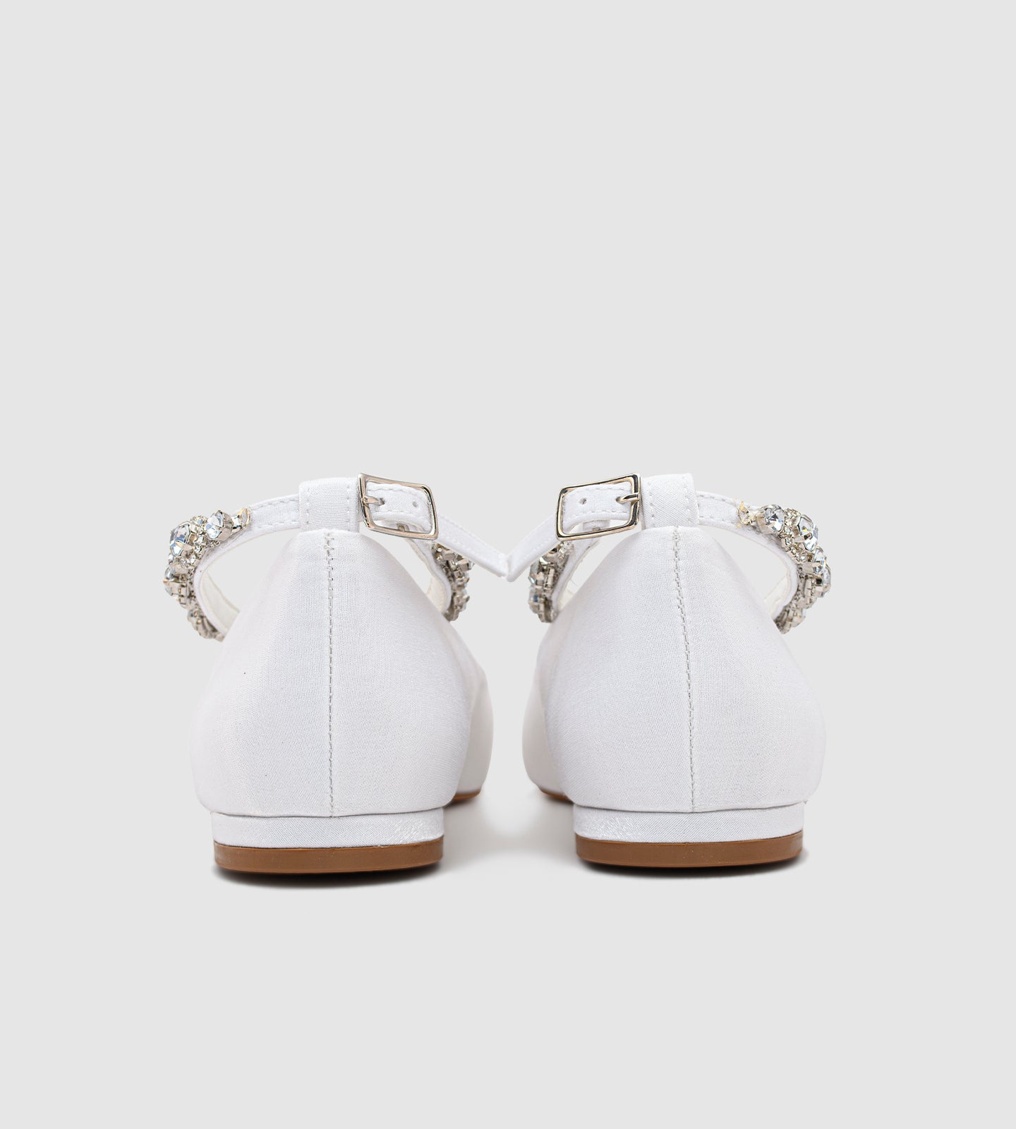 Sapatilha de noiva em material acetinado com acabamento perolado, design minimalista e tornozeleira delicada de strass, ideal para casamentos ao ar livre como no campo ou na praia.