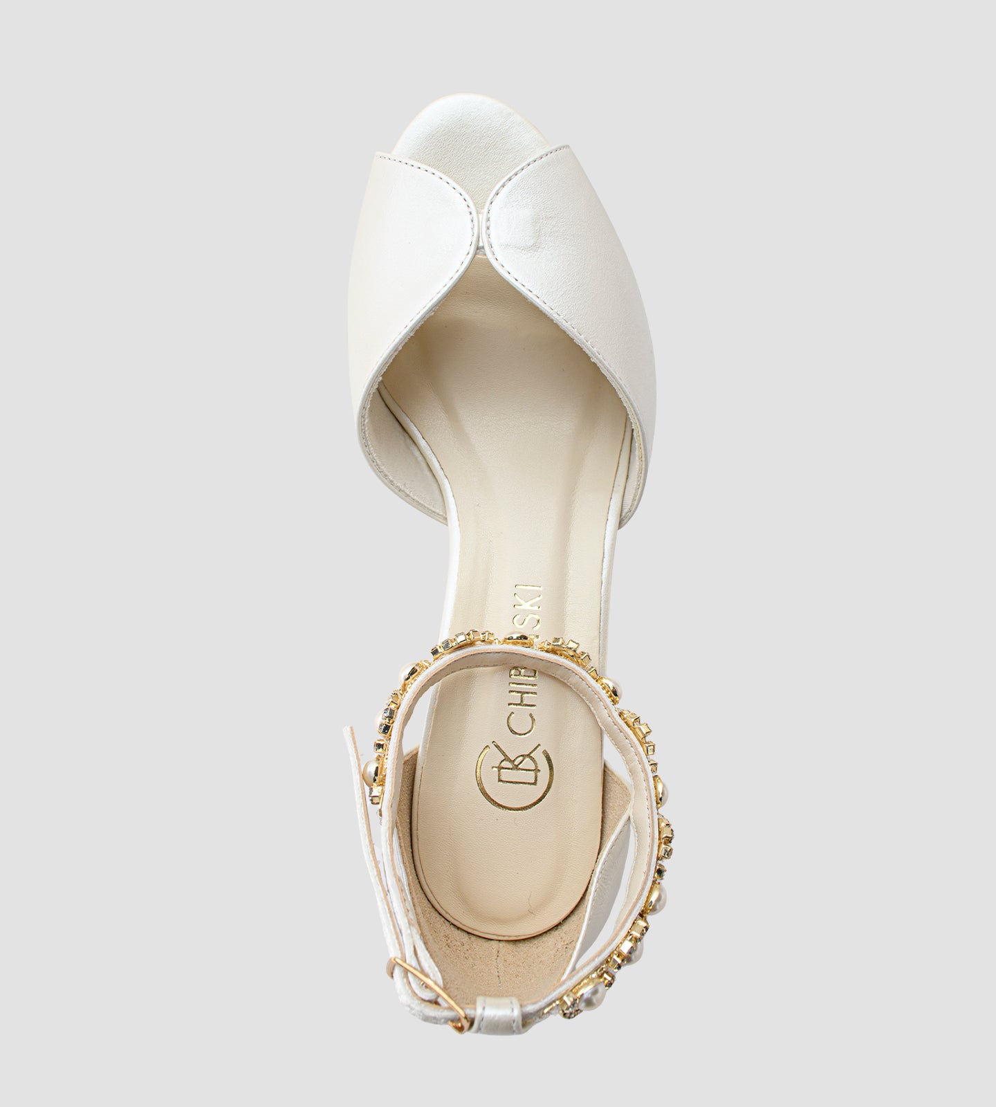 Sandália de noiva em couro perolado off-white com salto grosso de 5 cm, alça no tornozelo com fivela ajustável e tornozeleira de strass, combinando conforto, elegância e brilho sutil — ideal para cerimônias e festas de casamento.