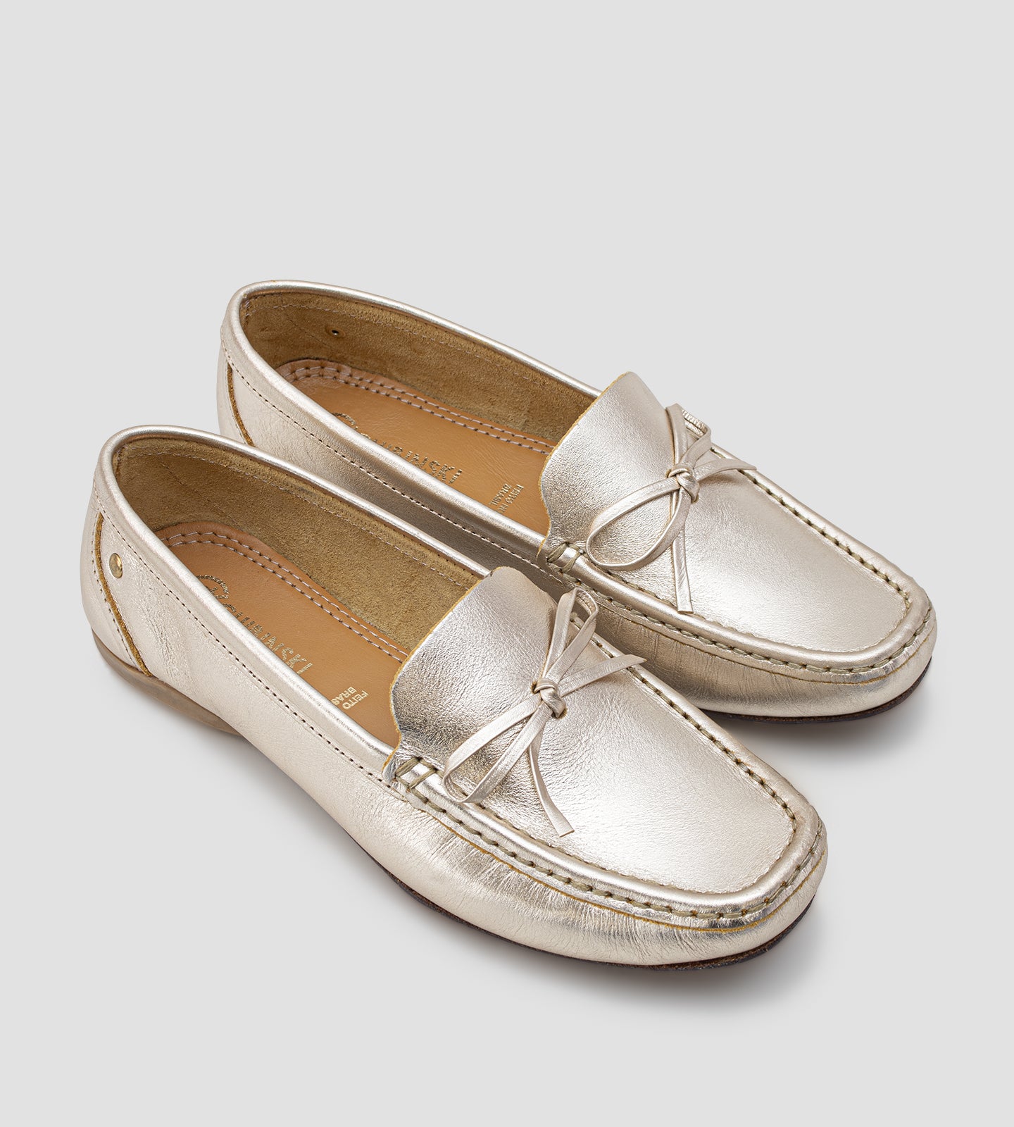 Mocassim feminino em couro legítimo dourado com laço frontal, acabamento sofisticado e design slip-on, ideal para looks elegantes e confortáveis no dia a dia.