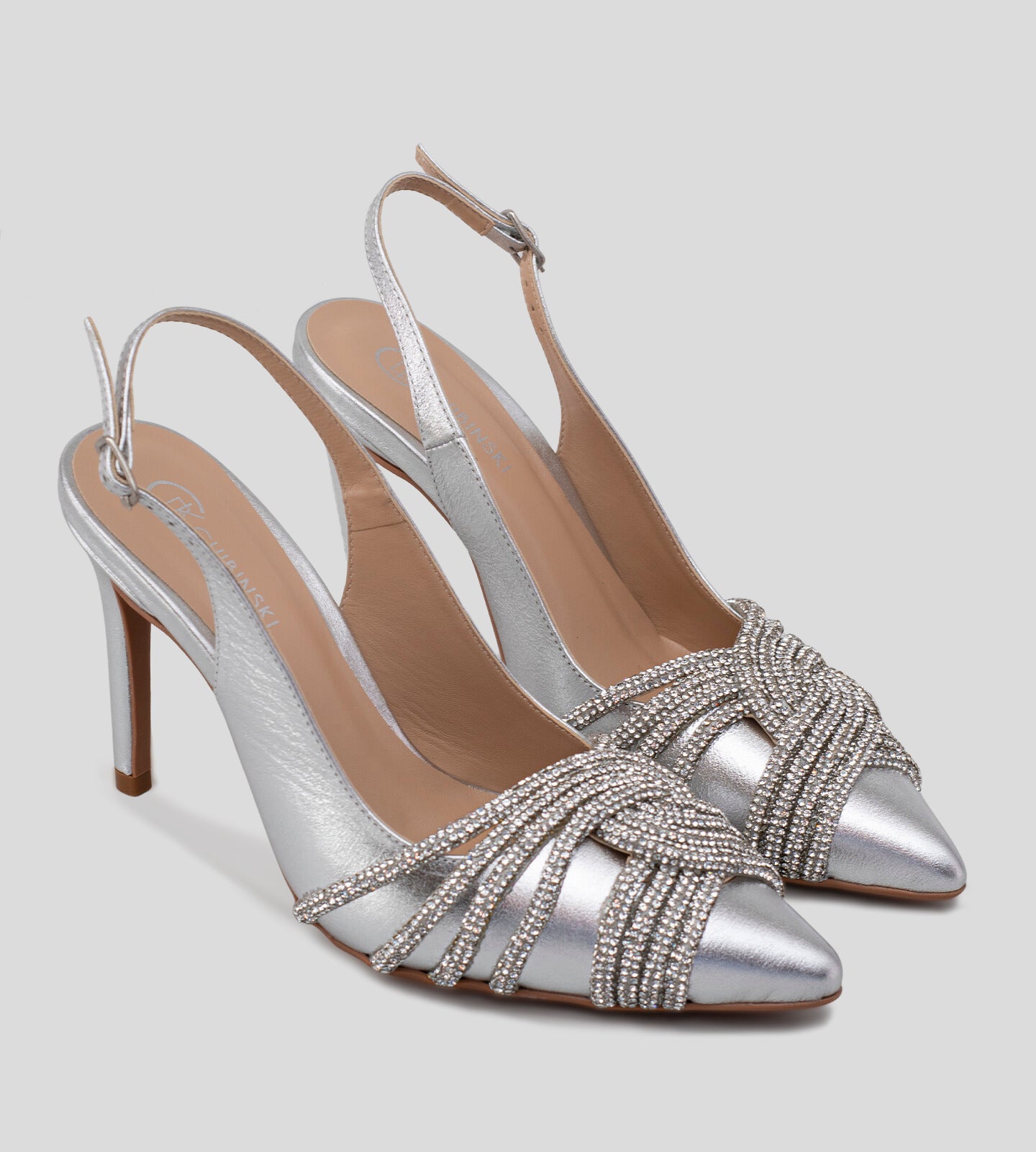 Scarpin slingback em couro prata com salto fino de 10 cm, adornado com detalhes em strass. O design sofisticado e brilhante é ideal para festas e ocasiões elegantes.