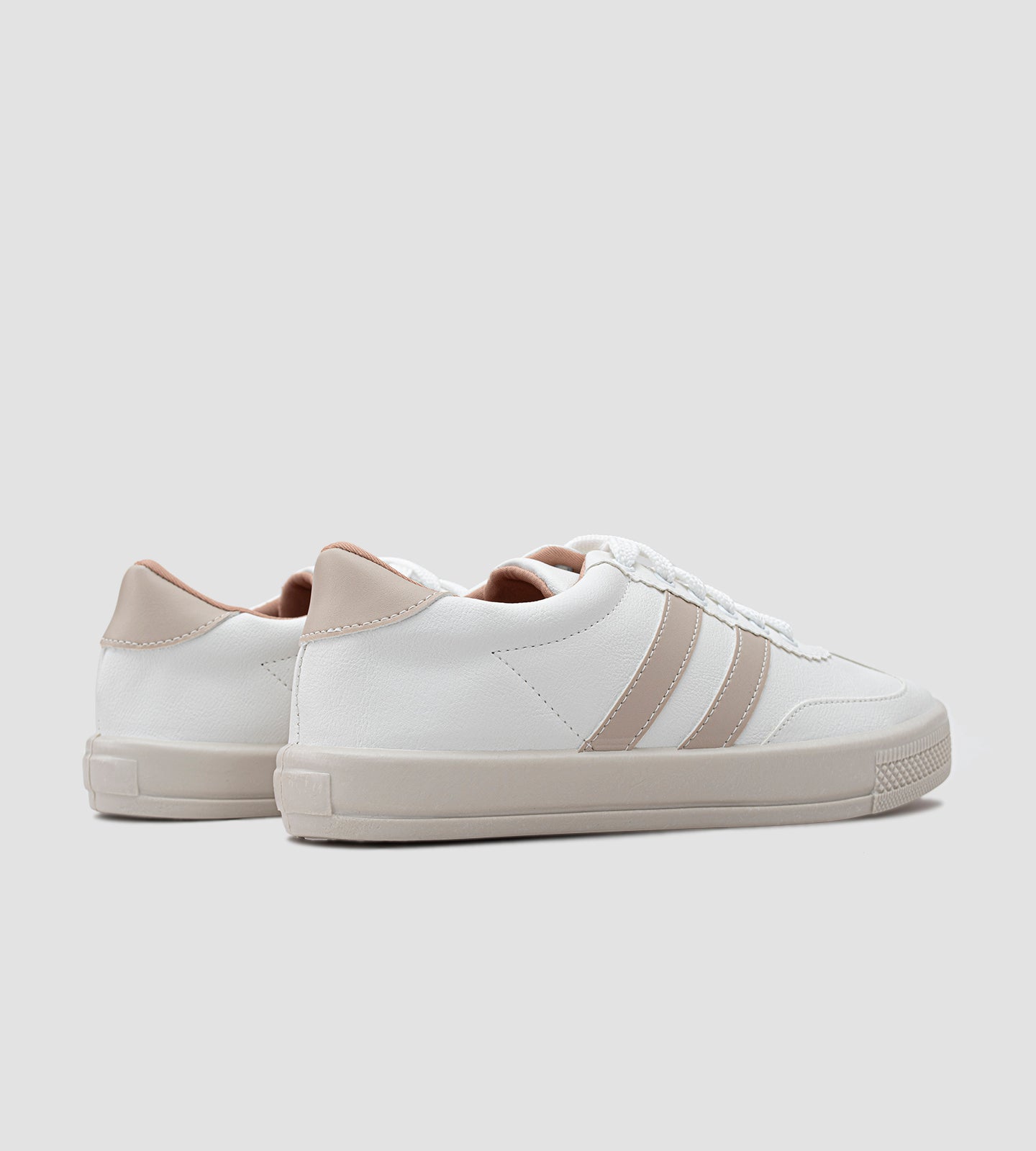 Tênis feminino branco com listras bege claro, detalhe nude no calcanhar, solado bege e fechamento em cadarço branco.