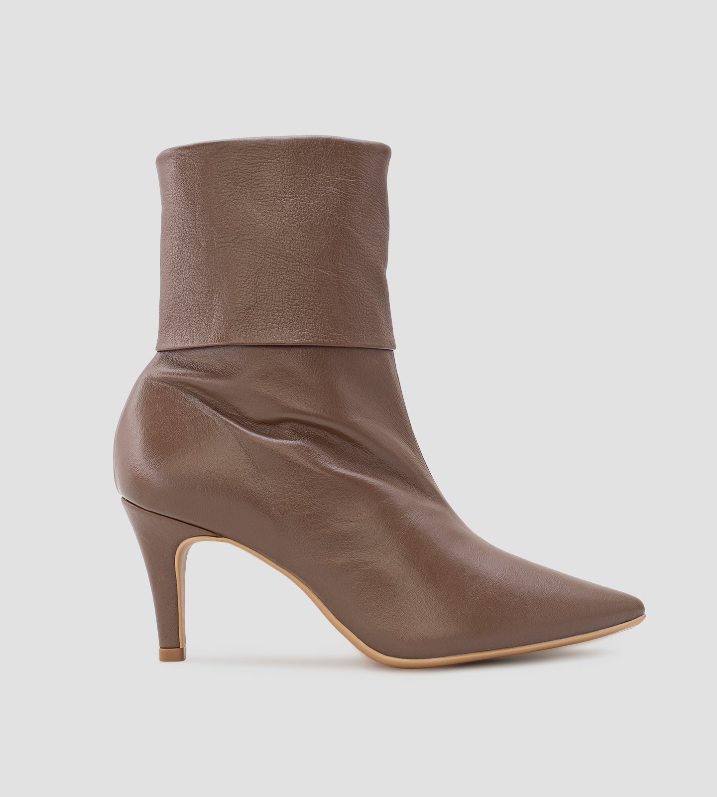 Bota feminina de cano médio em couro marrom. O modelo possui bico fino, salto fino de 8cm e um detalhe de dobra na parte superior do cano.