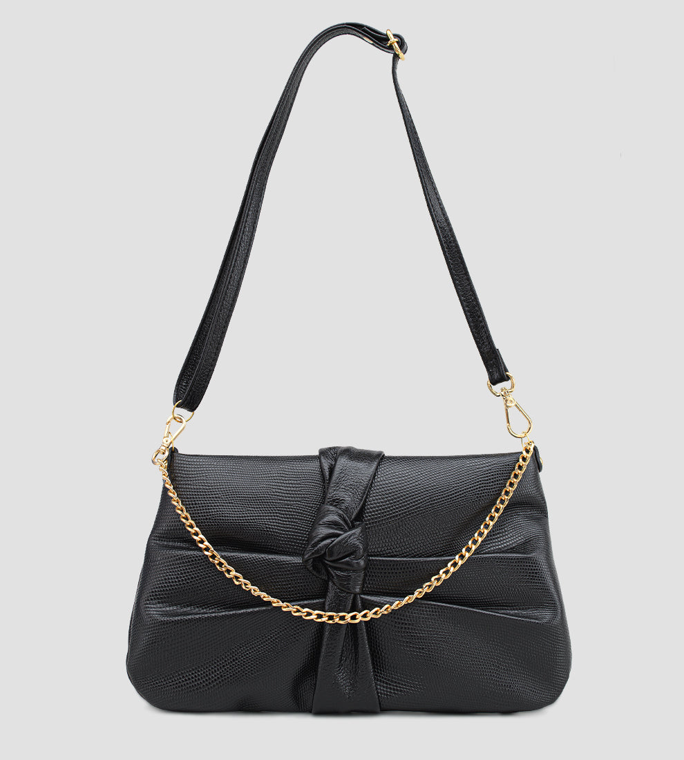 Bolsa feminina em couro preto com nó frontal, corrente dourada e alça ajustável removível.