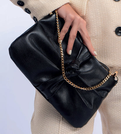 Bolsa feminina em couro preto com nó frontal, corrente dourada e alça ajustável removível.