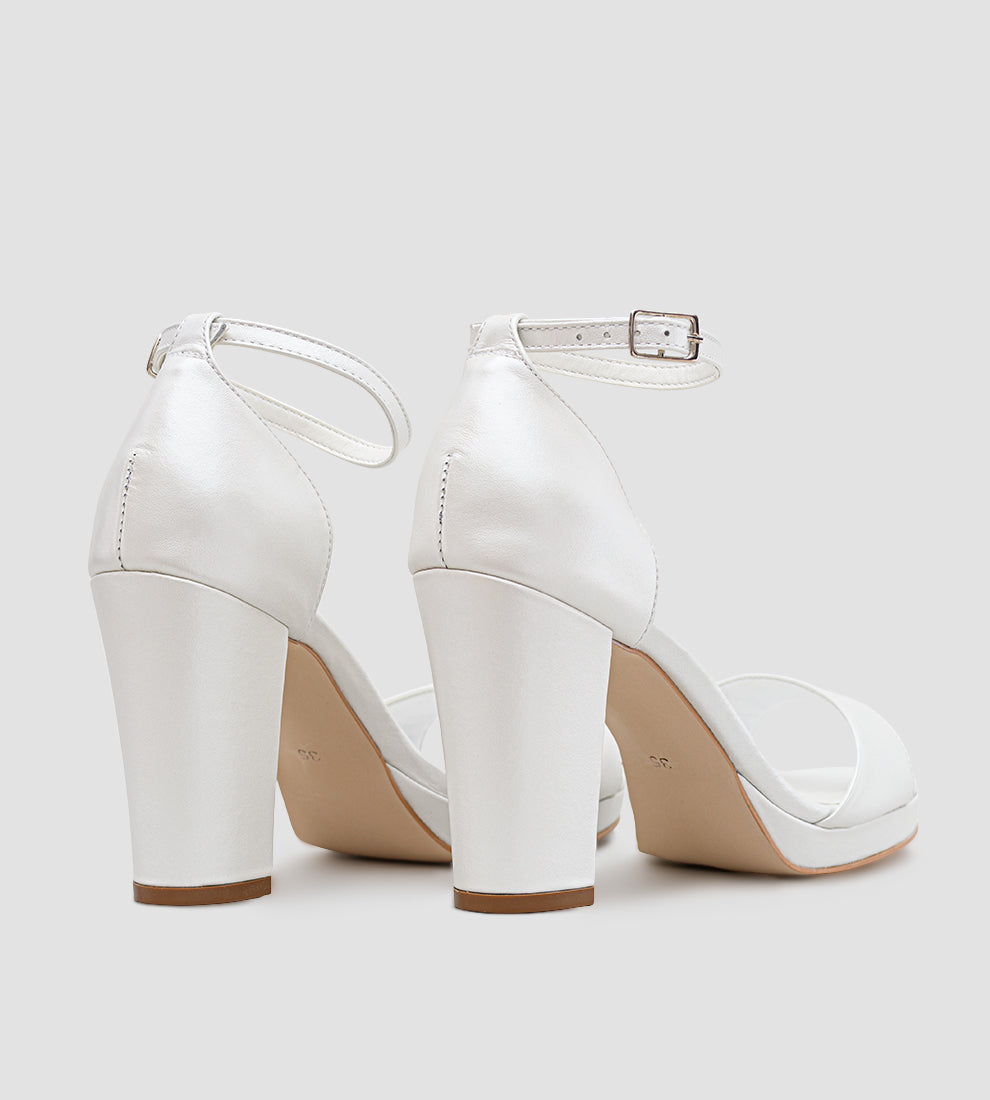 Sandália feminina em couro branco perolado, com meia-pata frontal e salto bloco de 10 cm, vista nos pés, com tira no tornozelo e acabamento elegante.