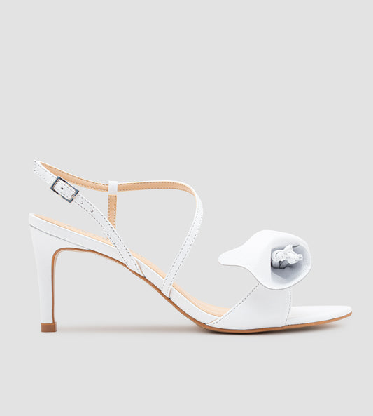 Sandália de noiva em couro branco com salto fino de 9 cm, tiras delicadas, detalhe floral artesanal na parte frontal e fechamento ajustável no tornozelo.