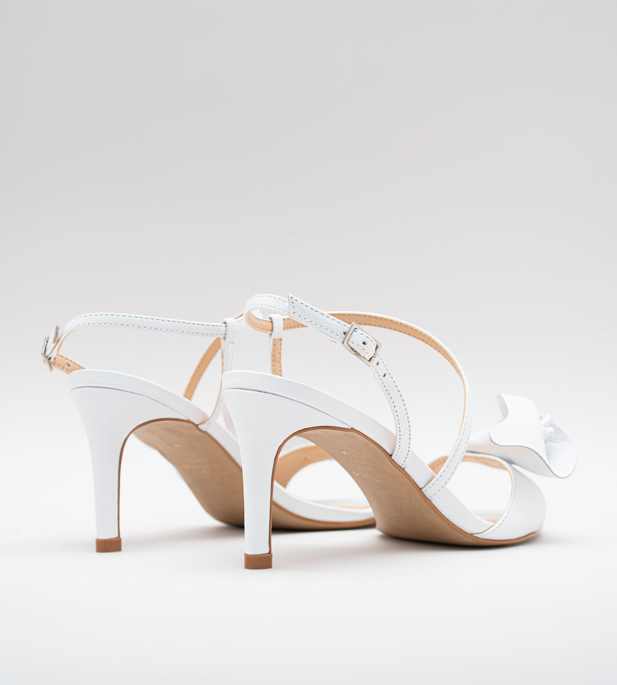 Sandália de noiva em couro branco com salto fino de 9 cm, tiras delicadas, detalhe floral artesanal na parte frontal e fechamento ajustável no tornozelo.
