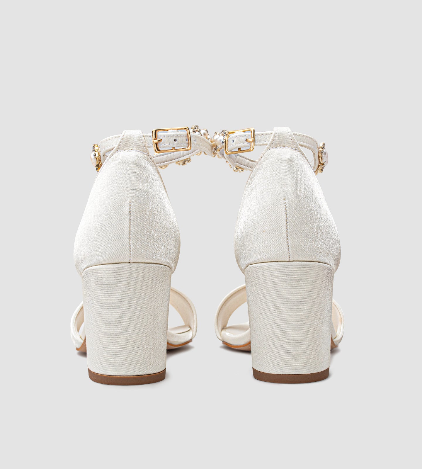 Sandália de noiva off-white em tecido velvet com brilho sutil, salto grosso de 7 cm, tira larga nos dedos e tornozeleira com pérolas e brilhos, unindo conforto, elegância e sofisticação para o grande dia.