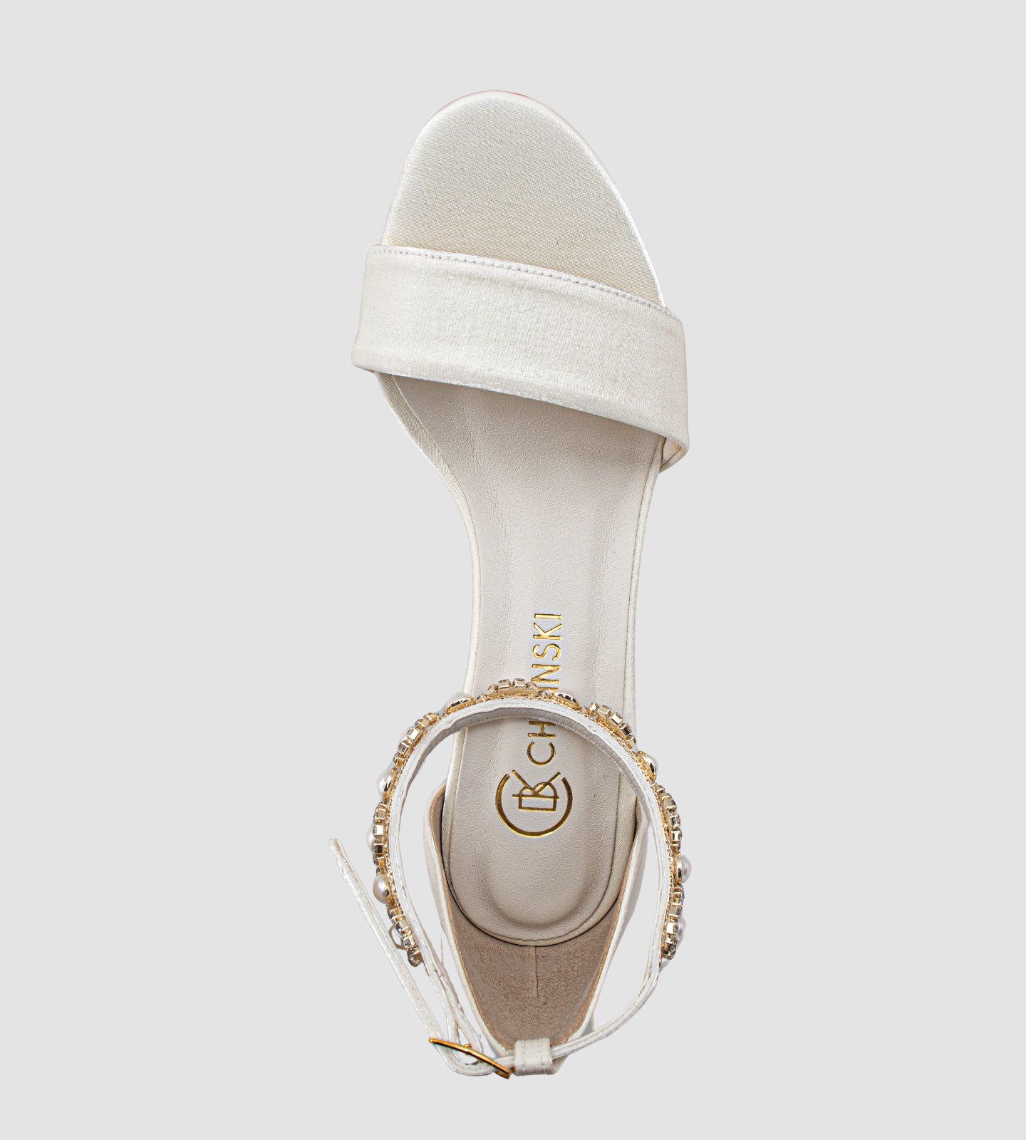 Sandália de noiva off-white em tecido velvet com brilho sutil, salto grosso de 7 cm, tira larga nos dedos e tornozeleira com pérolas e brilhos, unindo conforto, elegância e sofisticação para o grande dia.