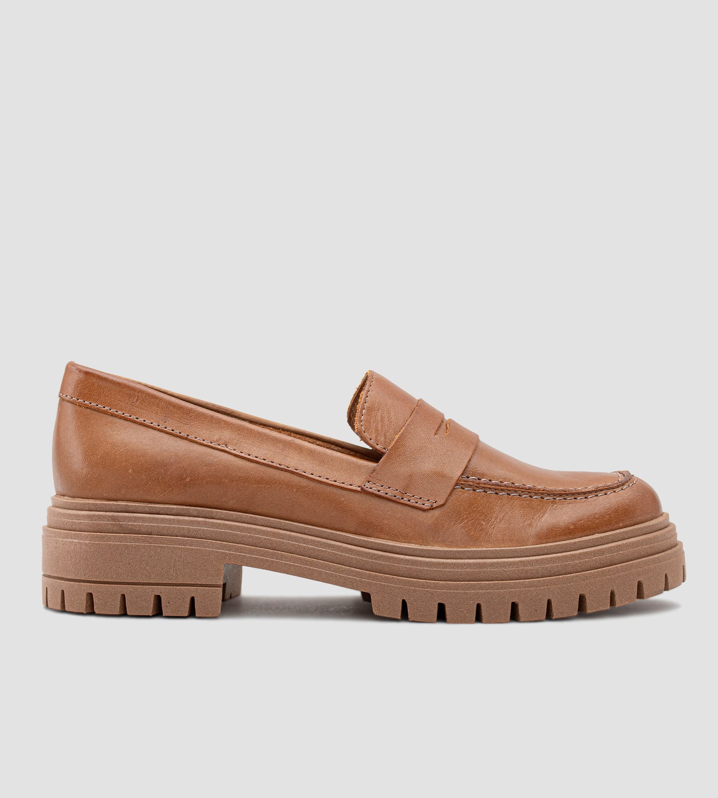 Mocassim feminino de couro marrom com salto tratorado, detalhe em costura aparente e sola robusta antiderrapante, ideal para looks modernos e elegantes.
