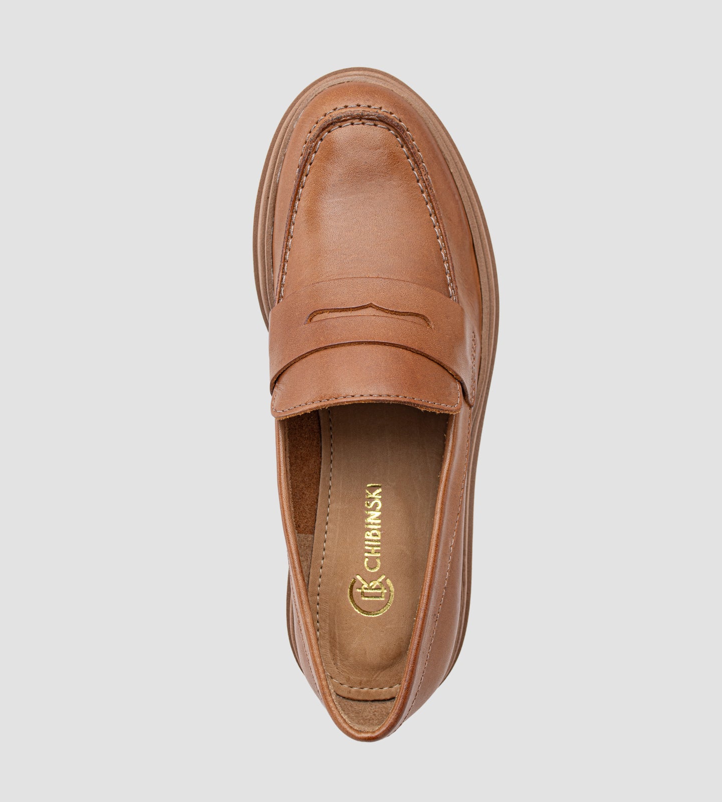 Mocassim feminino de couro marrom com salto tratorado, detalhe em costura aparente e sola robusta antiderrapante, ideal para looks modernos e elegantes.