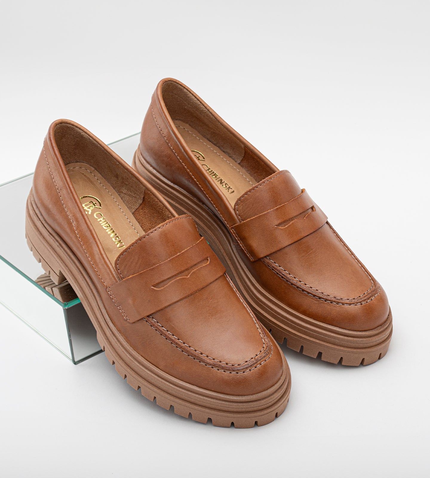 Mocassim feminino de couro marrom com salto tratorado, detalhe em costura aparente e sola robusta antiderrapante, ideal para looks modernos e elegantes.