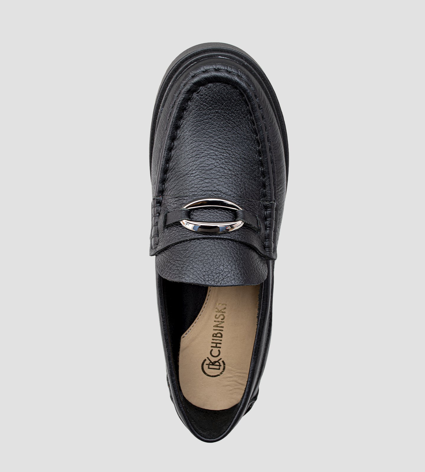Mocassim feminino em couro preto com solado tratorado e detalhe metálico.