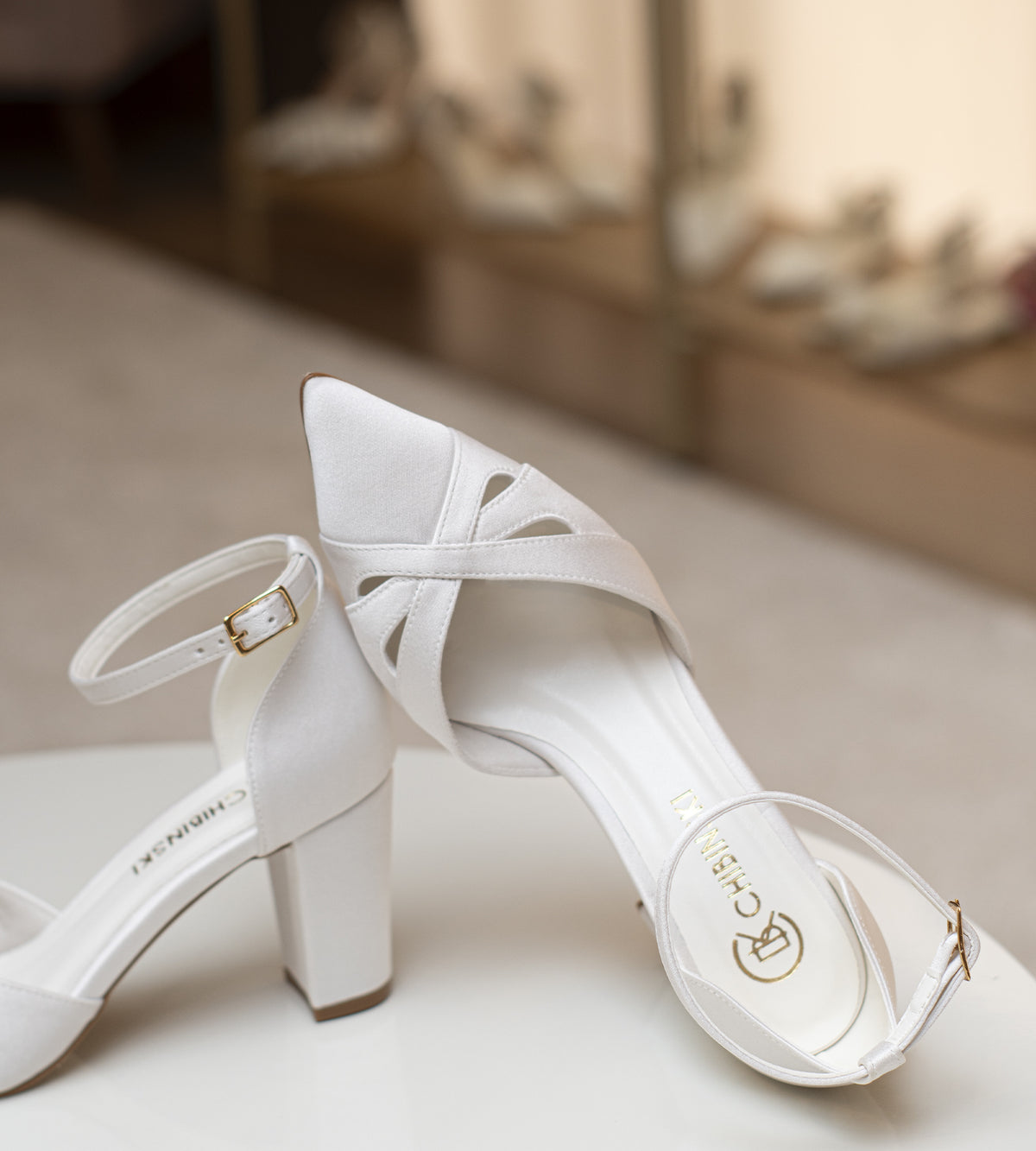 Scarpin de noiva CHIBINSKI off-white em tecido acetinado Indonésia, com bico fino, recortes delicados no cabedal, tira ajustável no tornozelo e salto bloco de 7 cm, ideal para casamento civil, cerimônia religiosa e festas.