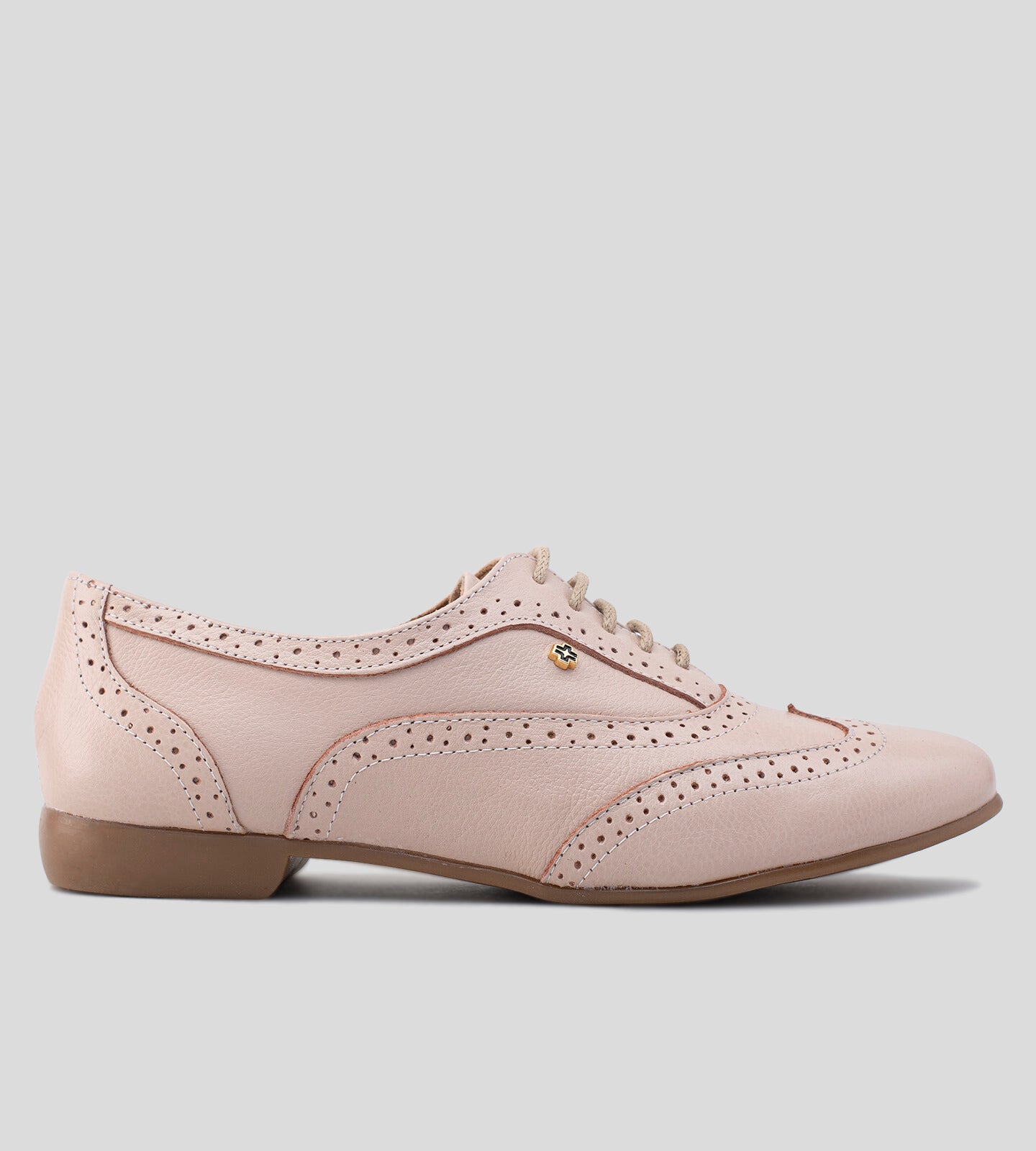 Sapato Oxford feminino em couro rosê, com acabamento sofisticado e detalhes brogue perfurados. Modelo de amarração com cadarço, solado baixo em tom neutro e bico levemente arredondado. Design clássico e elegante, ideal para compor looks casuais e refinados.