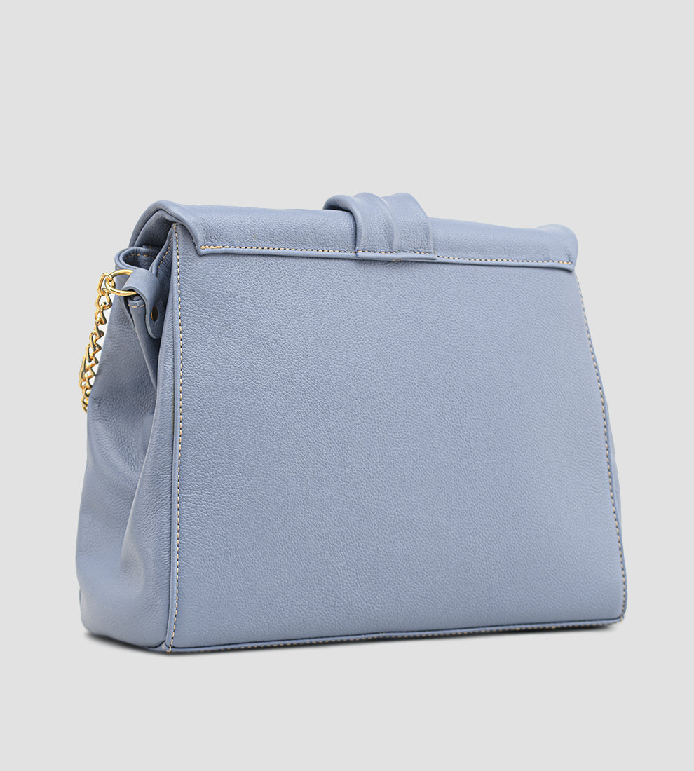 Bolsa feminina em couro azul com detalhe de nó, corrente dourada e alça ajustável, usada no ombro.