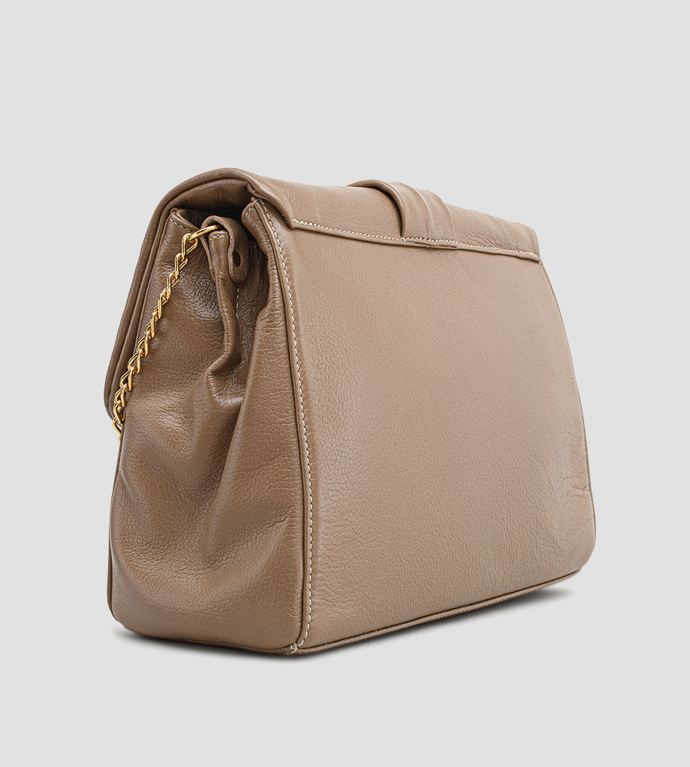 Bolsa feminina em couro marrom com detalhe de nó, corrente dourada e alça ajustável, usada no ombro.