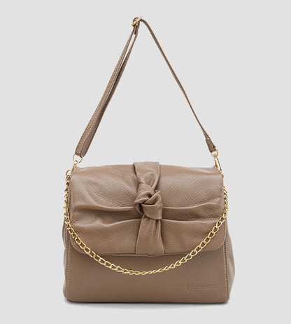 Bolsa feminina em couro marrom com detalhe de nó, corrente dourada e alça ajustável, usada no ombro.