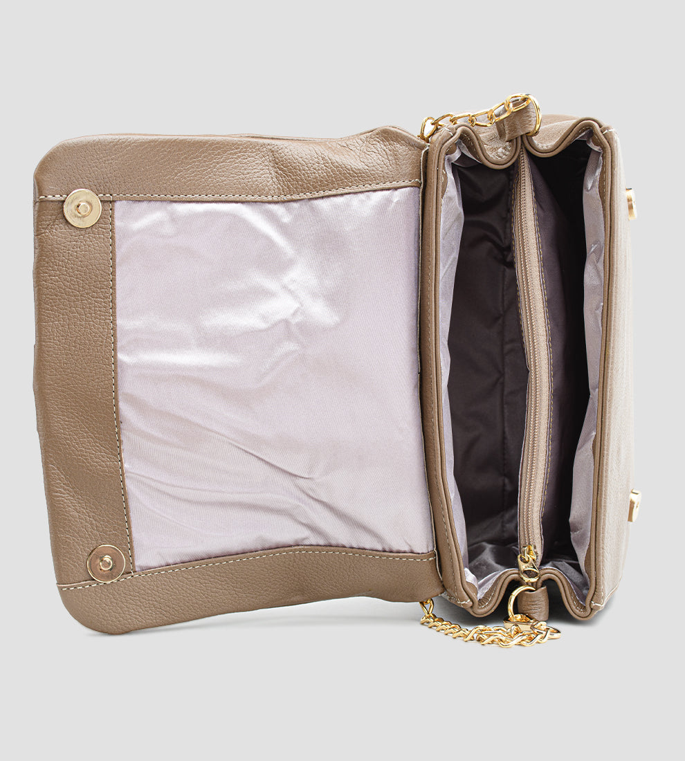 Bolsa feminina em couro marrom com detalhe de nó, corrente dourada e alça ajustável, usada no ombro.