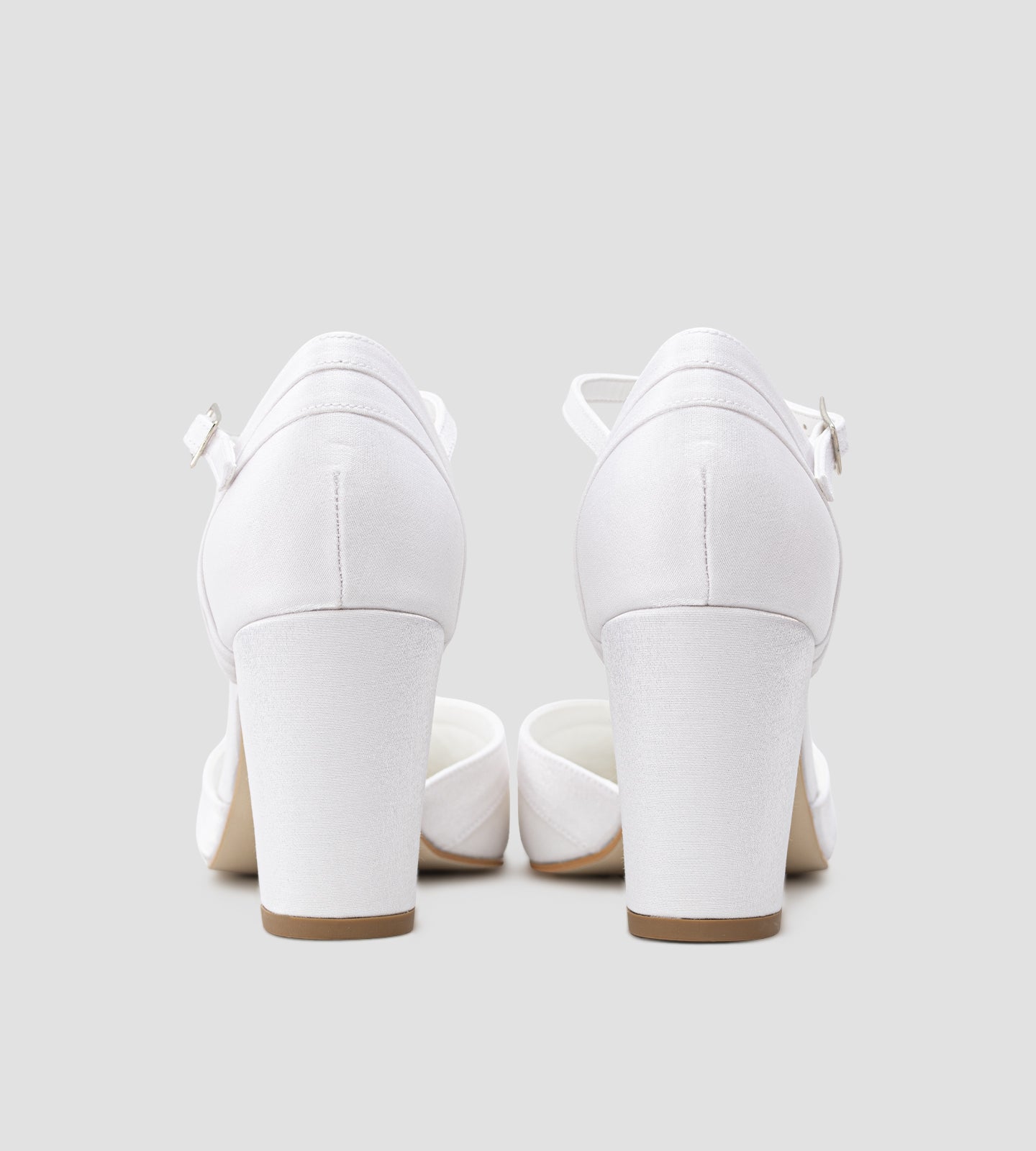 Sapato de noiva scarpin branco em tecido velvet, com bico fino, salto bloco médio de 7 cm e tira no tornozelo com fivela, exibido nos pés com calça clara.