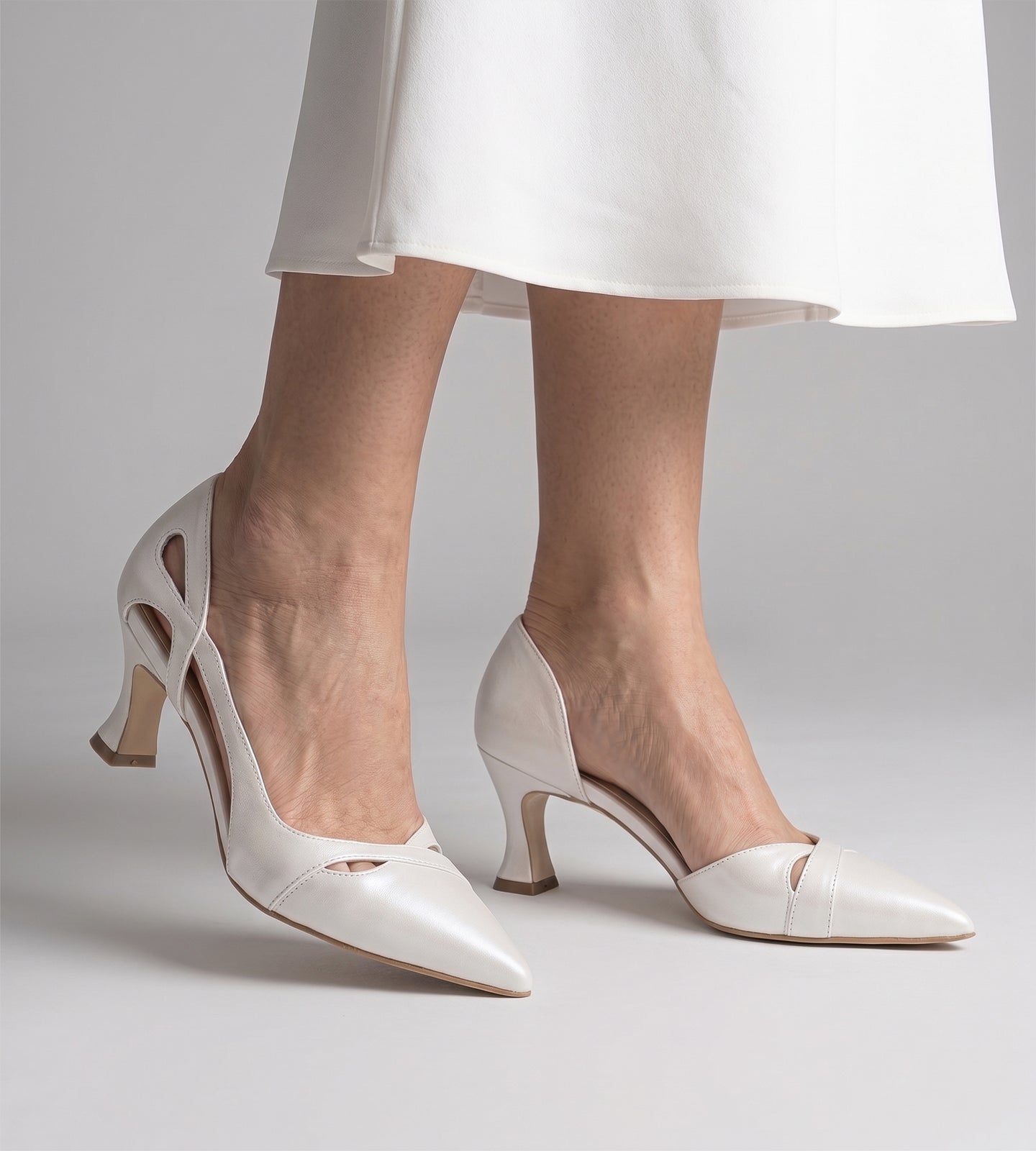 Scarpin de noiva em couro branco perolado, com bico fino, recortes laterais delicados e salto taça de 7 cm.