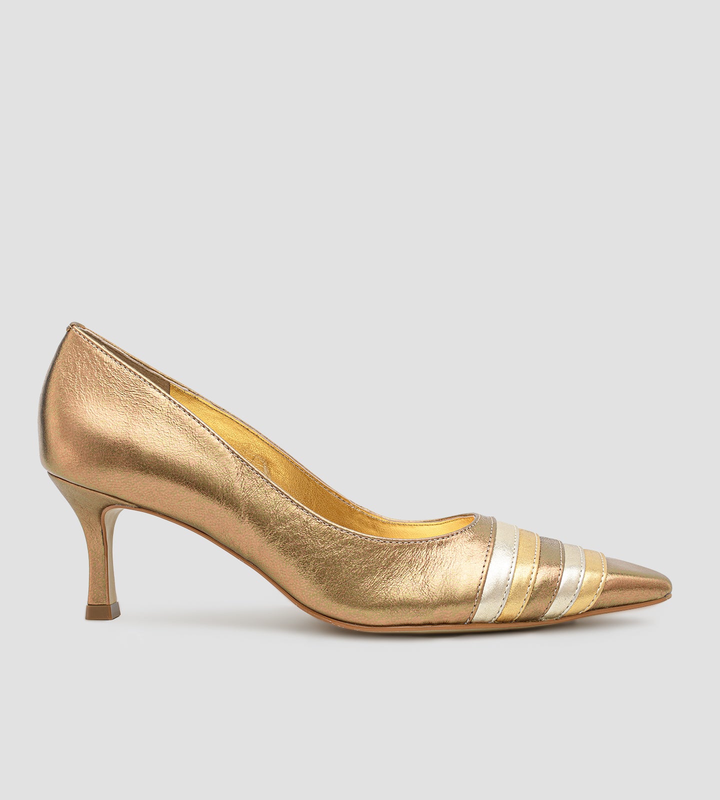 Vista lateral de um scarpin feminino de couro na cor bronze metalizado. O sapato possui bico fino com um detalhe frontal de tiras metálicas sobrepostas em tons alternados de dourado claro e bronze. O salto é médio, de 7cm, com um design fino que se alarga levemente na base. Fundo liso cinza claro.