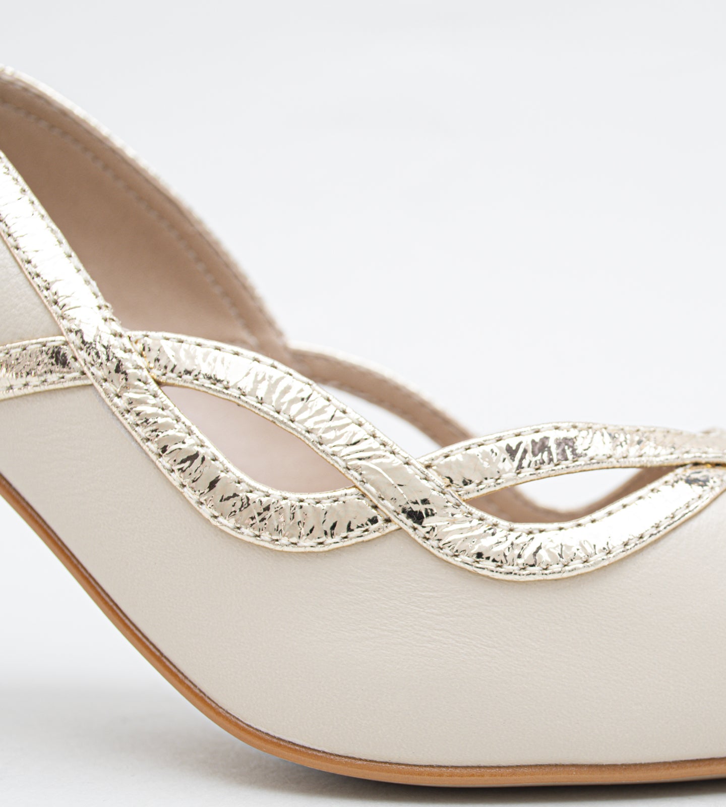scarpin feminino em couro bege claro com salto fino de 8cm, bico fino e detalhe ondulado metalizado sofisticado.