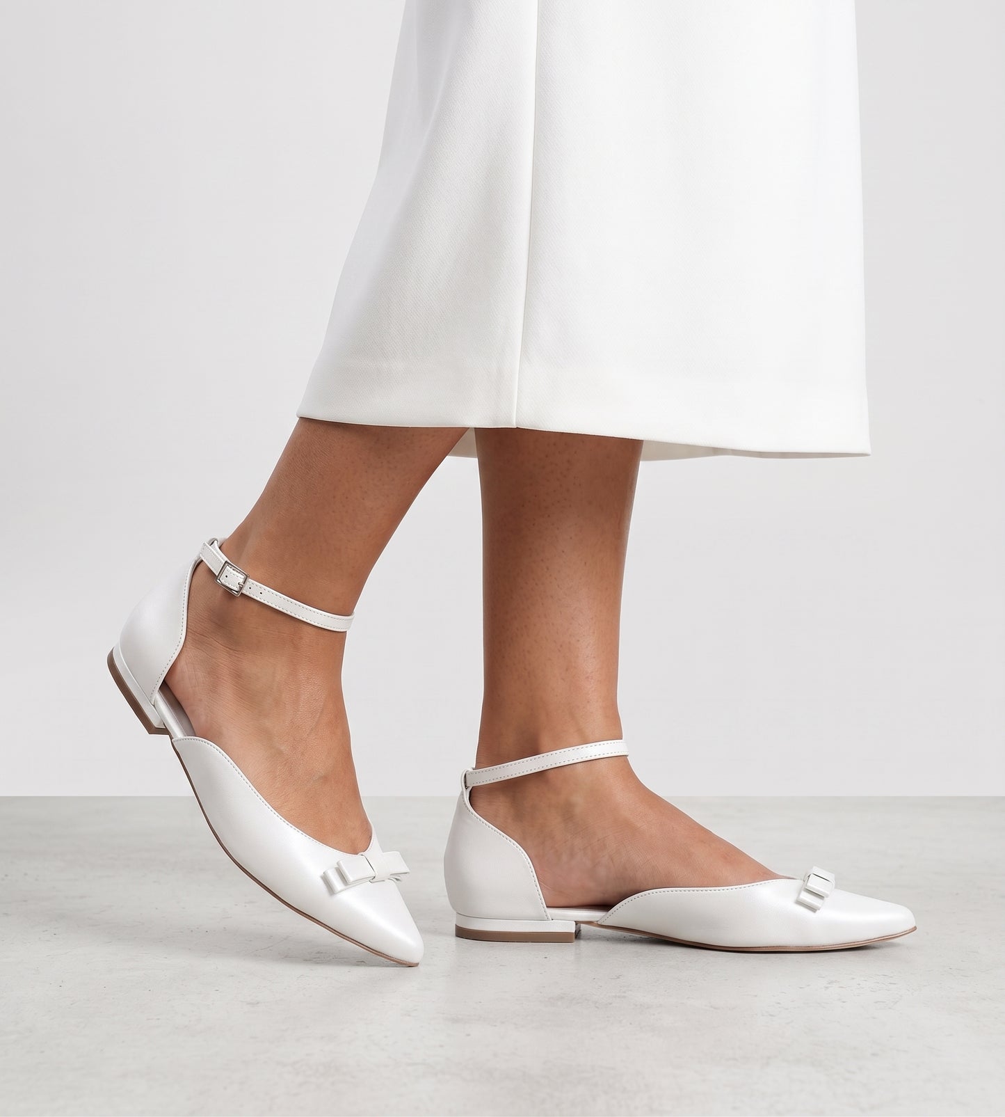Sapatilha de noiva em couro perolado branco com laço delicado na parte frontal, design elegante e confortável.